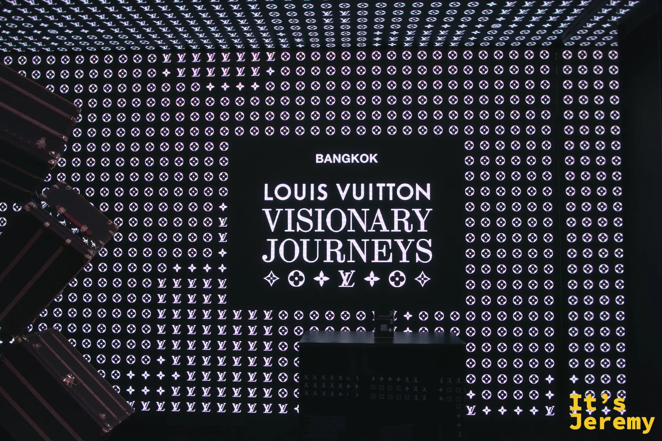 展覽入口黑底白字招牌，LV monogram 滿版背景，BANGKOK LOUIS VUITTON VISIONARY JOURNEYS