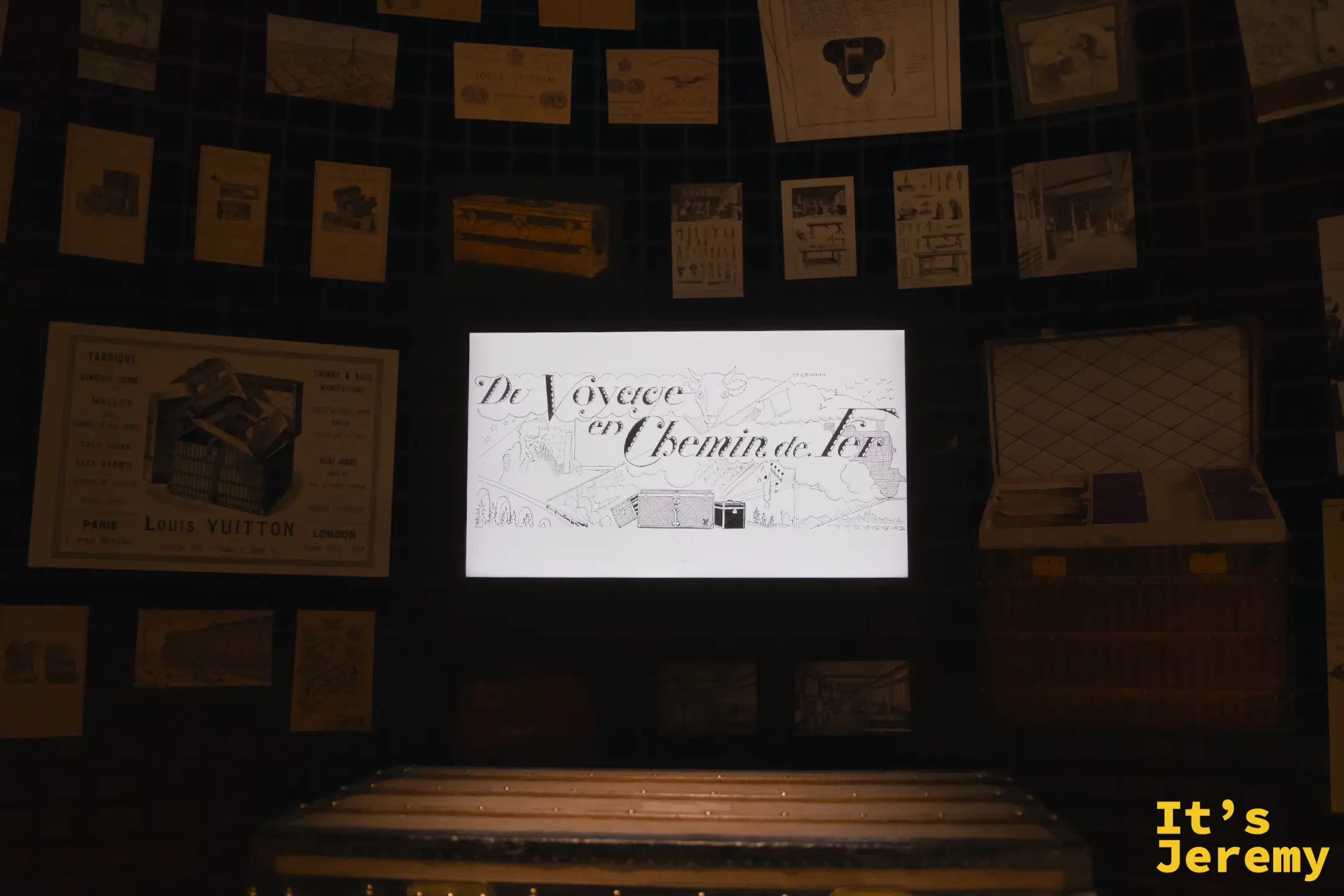 歷史展區螢幕播放《Du Voyage en Chemin de Fer》手繪動畫，周圍貼滿 LV 各年代廣告海報與設計圖