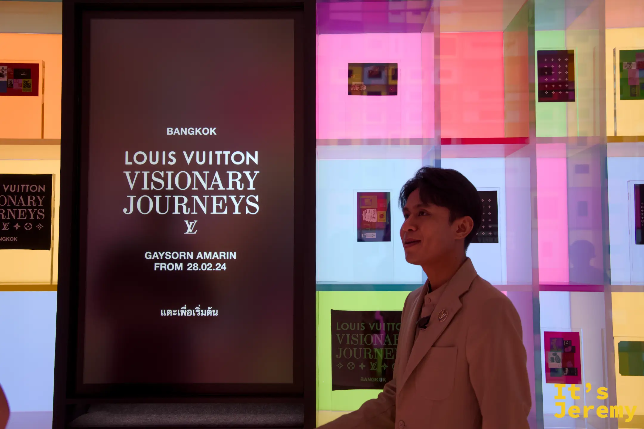 Souvenirs 展間扭蛋機螢幕，顯示 BANGKOK LOUIS VUITTON VISIONARY JOURNEYS 主視覺，背後是繽紛色彩拼貼牆
