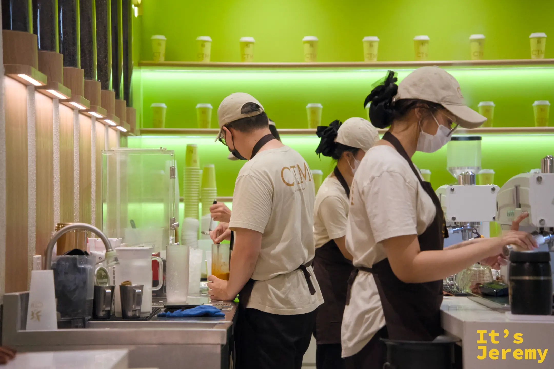 四位 CTM 店員在電黃色吧台後各守一道工序