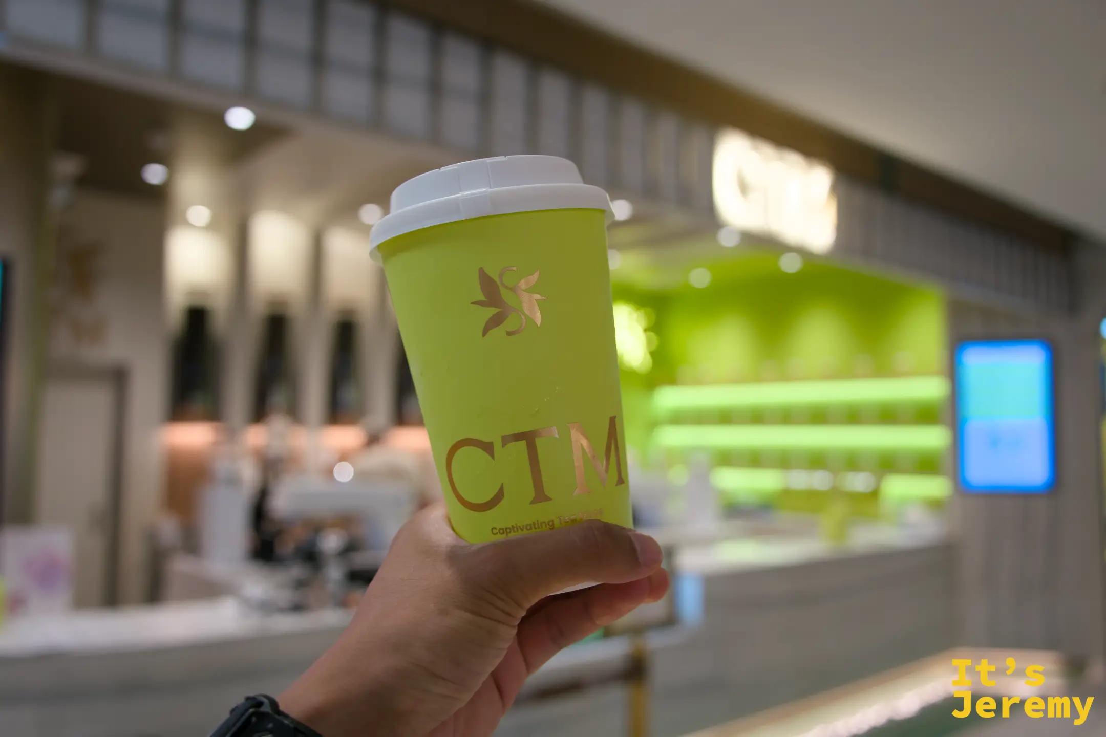 手持 CTM 標誌性黃色外帶杯，背景是 CTM Central Park 門市
