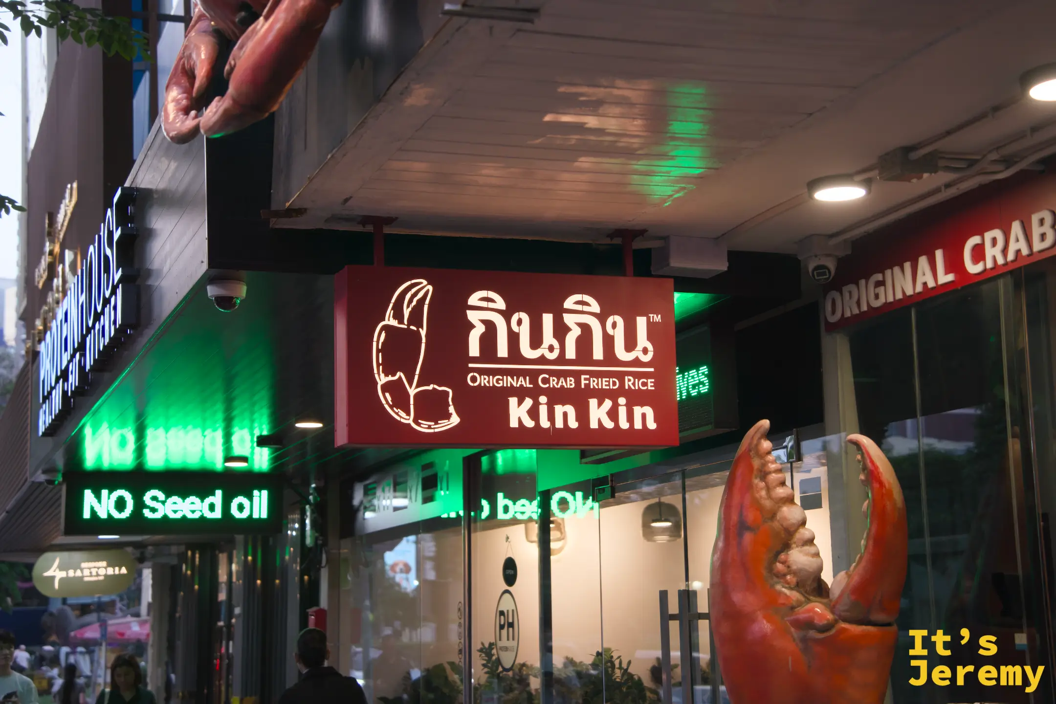 入夜的招牌燈箱近照：「กินกิน Original Crab Fried Rice Kin Kin」，紅配綠霓虹，是蘇坤蔚路上標準的曼谷夜晚配色