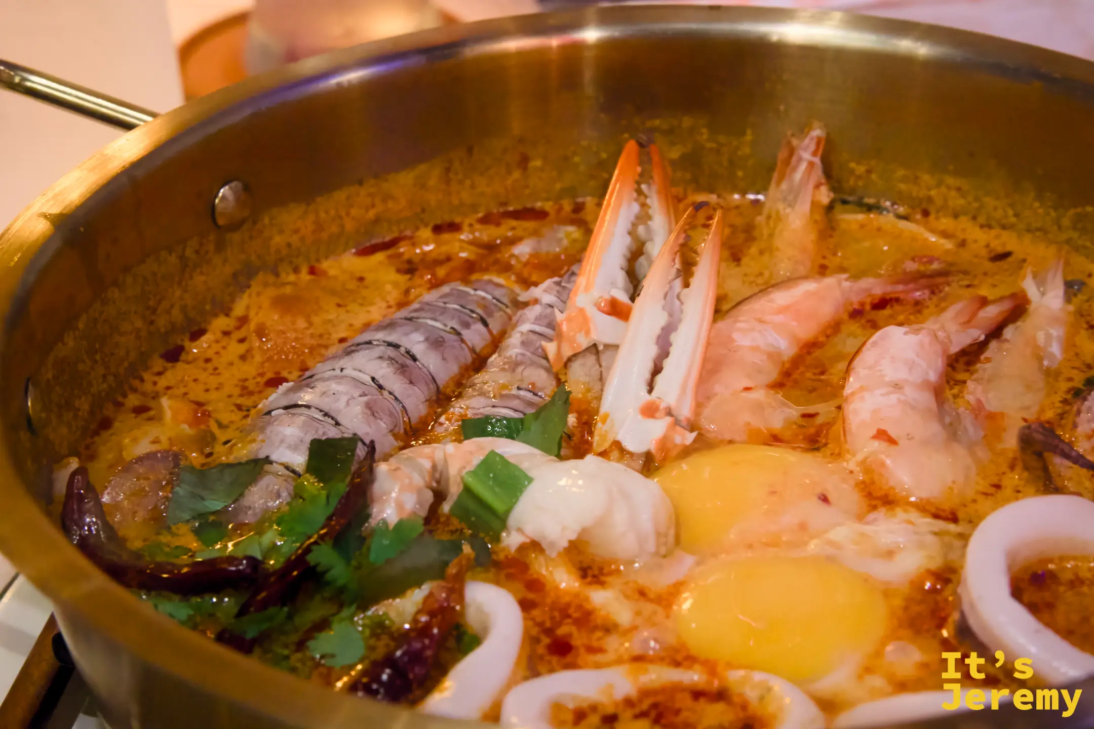 銅鍋裡的冬陰功海鮮媽媽麵鍋：大蝦、蟹腳、中卷、半熟蛋，湯底橘紅厚實，掀蓋的瞬間香氣直衝上來