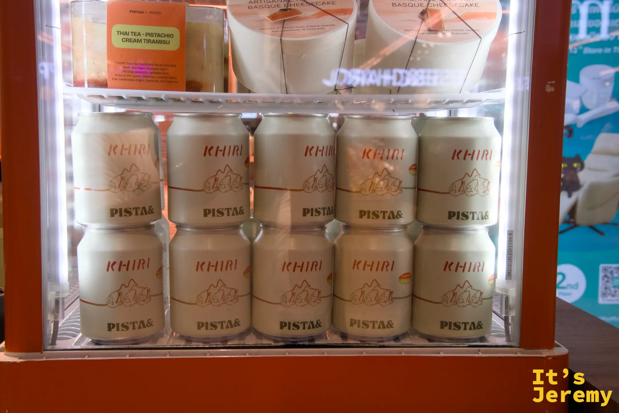 展示冰箱另一層:KHIRI × PISTA& 聯名罐裝佔滿整排,上層放著 Basque Cheesecake 和 Tiramisu 聯名甜點