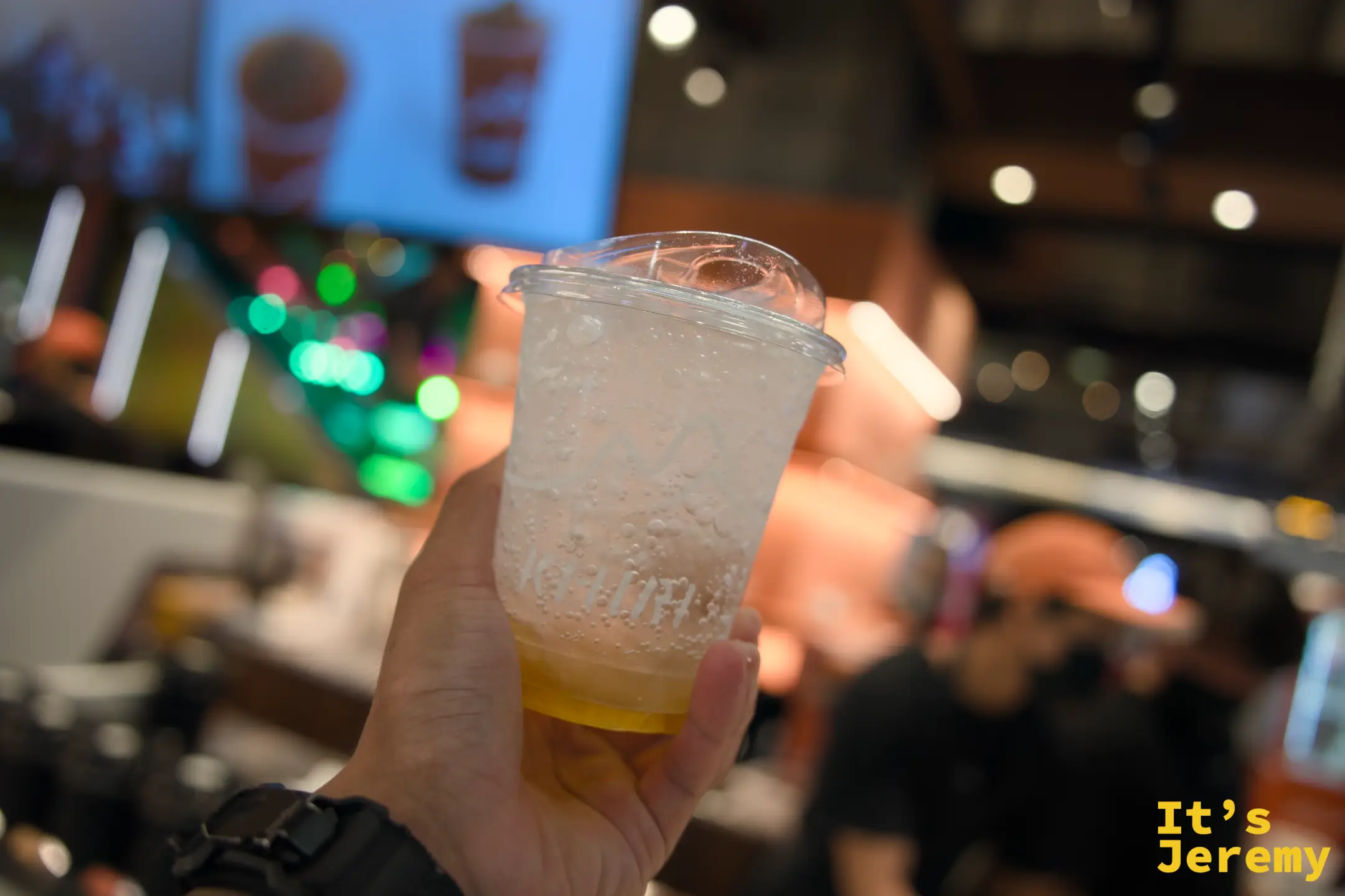 手持一杯 Yuzu Plum Fizz,Emsphere 商場燈光在背景暈開