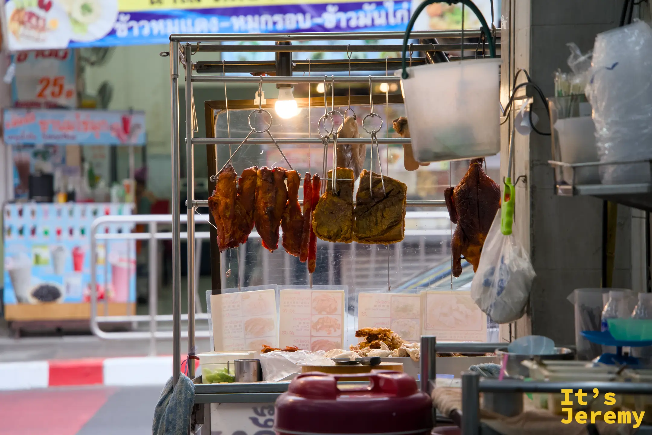 灶龍店門口側面,燈光下掛著整排烤豬肉,背後是石龍軍路的街道景色