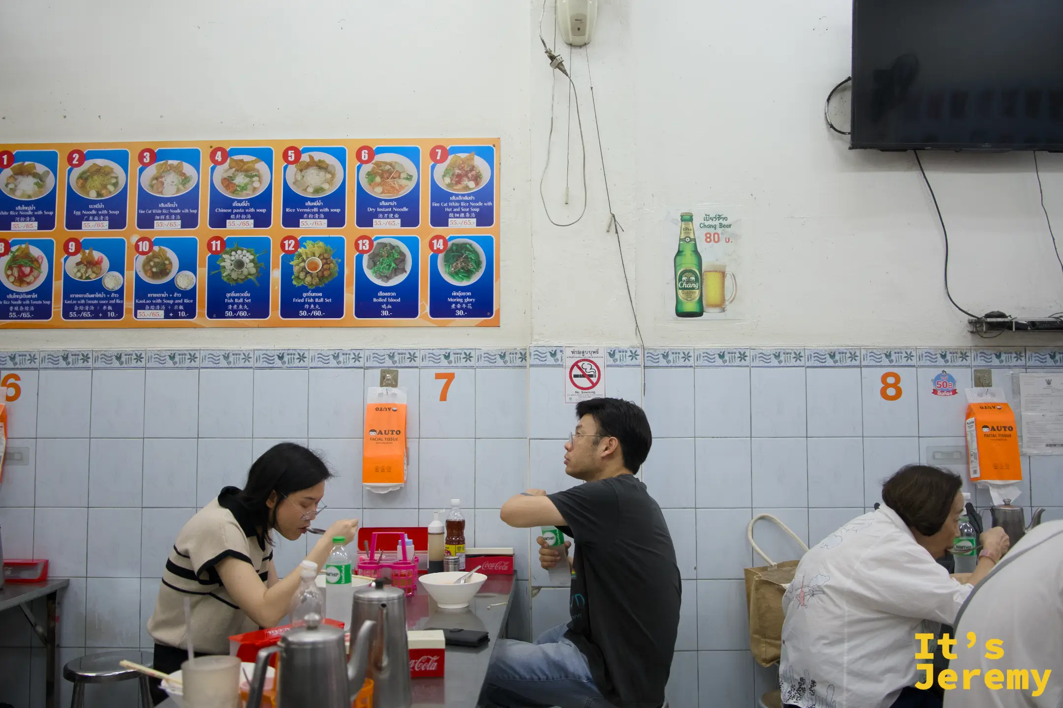 店內用餐場景:桌椅排列整齊,牆上掛著彩色圖片菜單板,客人安靜地在座位上吃麵,桌面標有數字編號