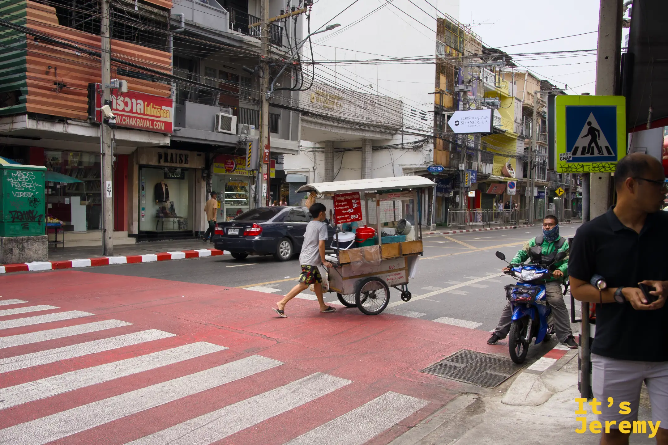 石龍軍路十字路口,少年推著附有菜單招牌的流動餐車穿越斑馬線