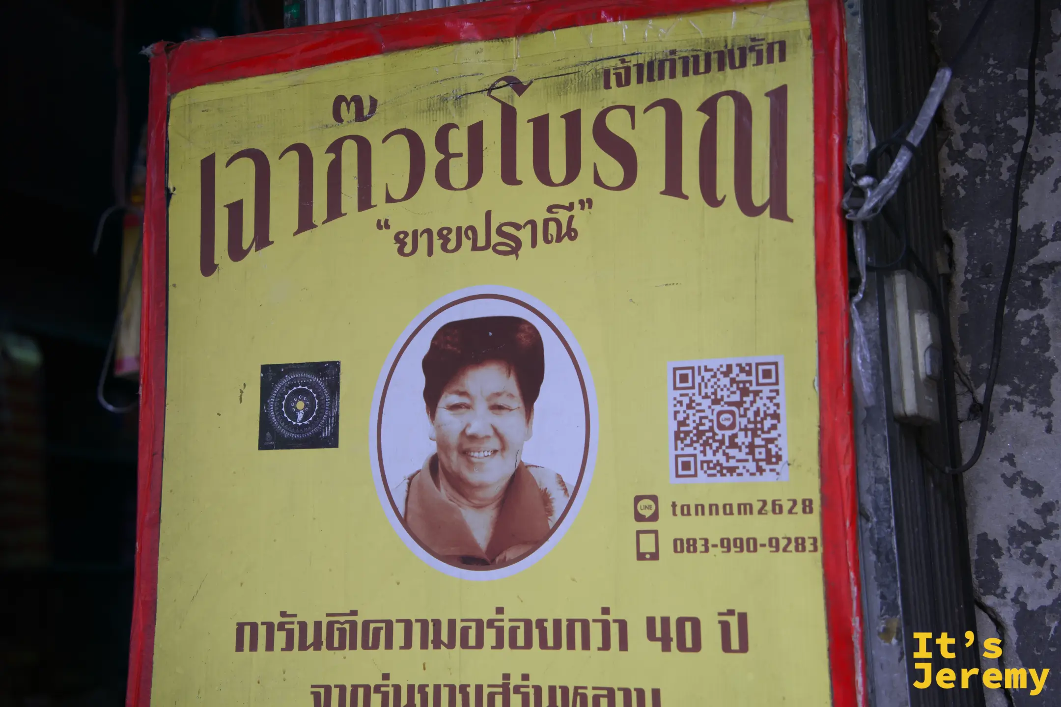 Charoen Krung 路邊攤的黃底紅框招牌，寫著「เฉาก๊วยโบราณ ยายปราณี」與保證40年美味的文字，附有創始人阿嬤的肖像照