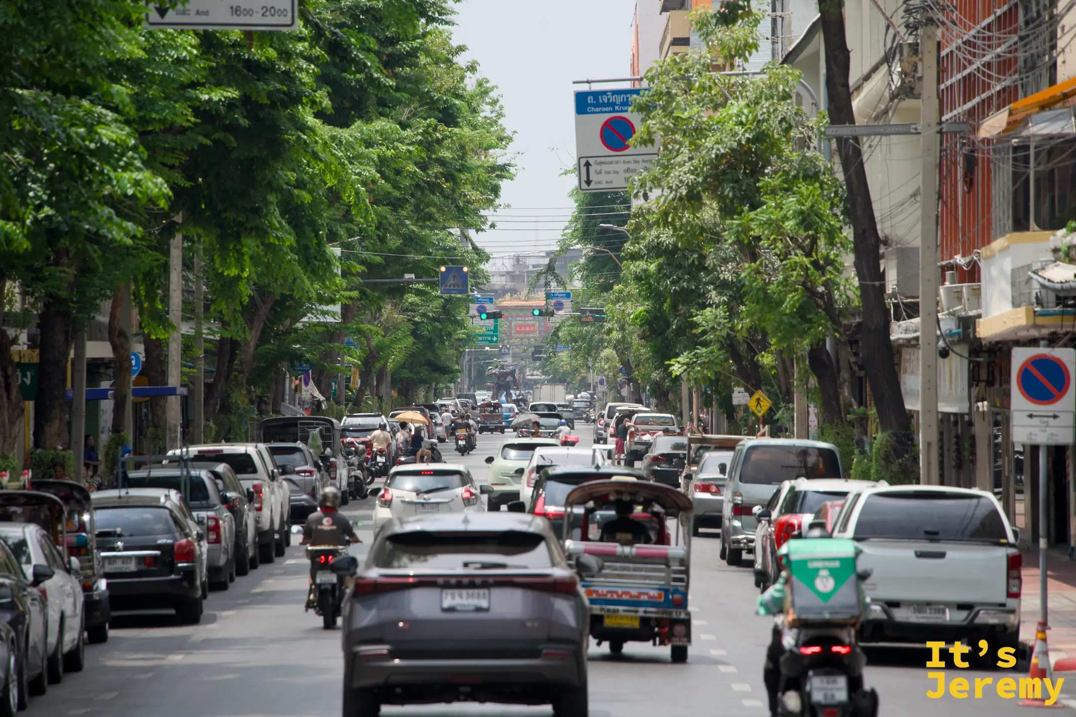 石龍軍路主幹道的白天車流,兩側行道樹,嘟嘟車在其中