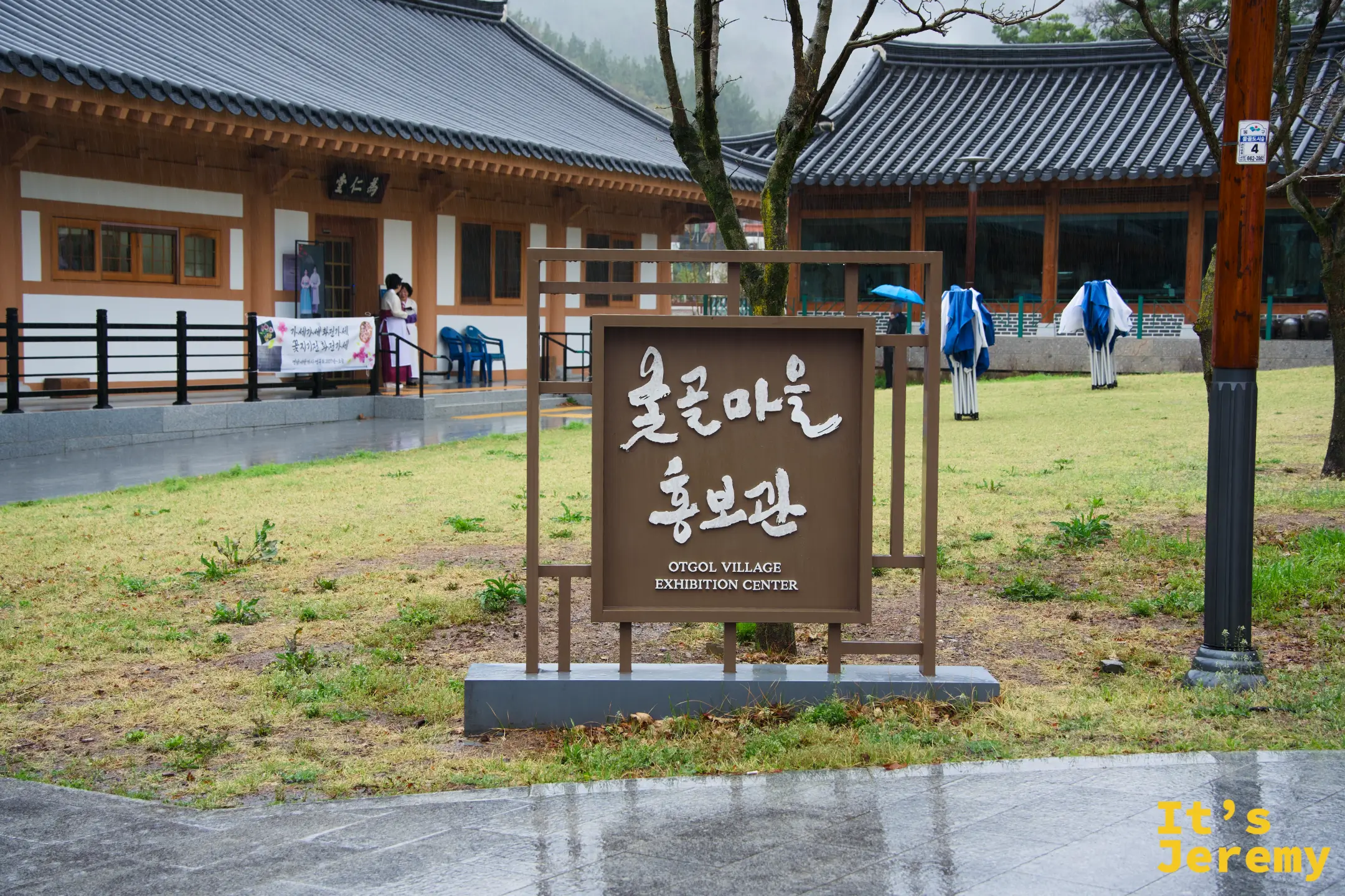 옻골마을홍보관（展覽館）入口，招牌後方是雨中的傳統韓屋，遠處可見馬造型裝置