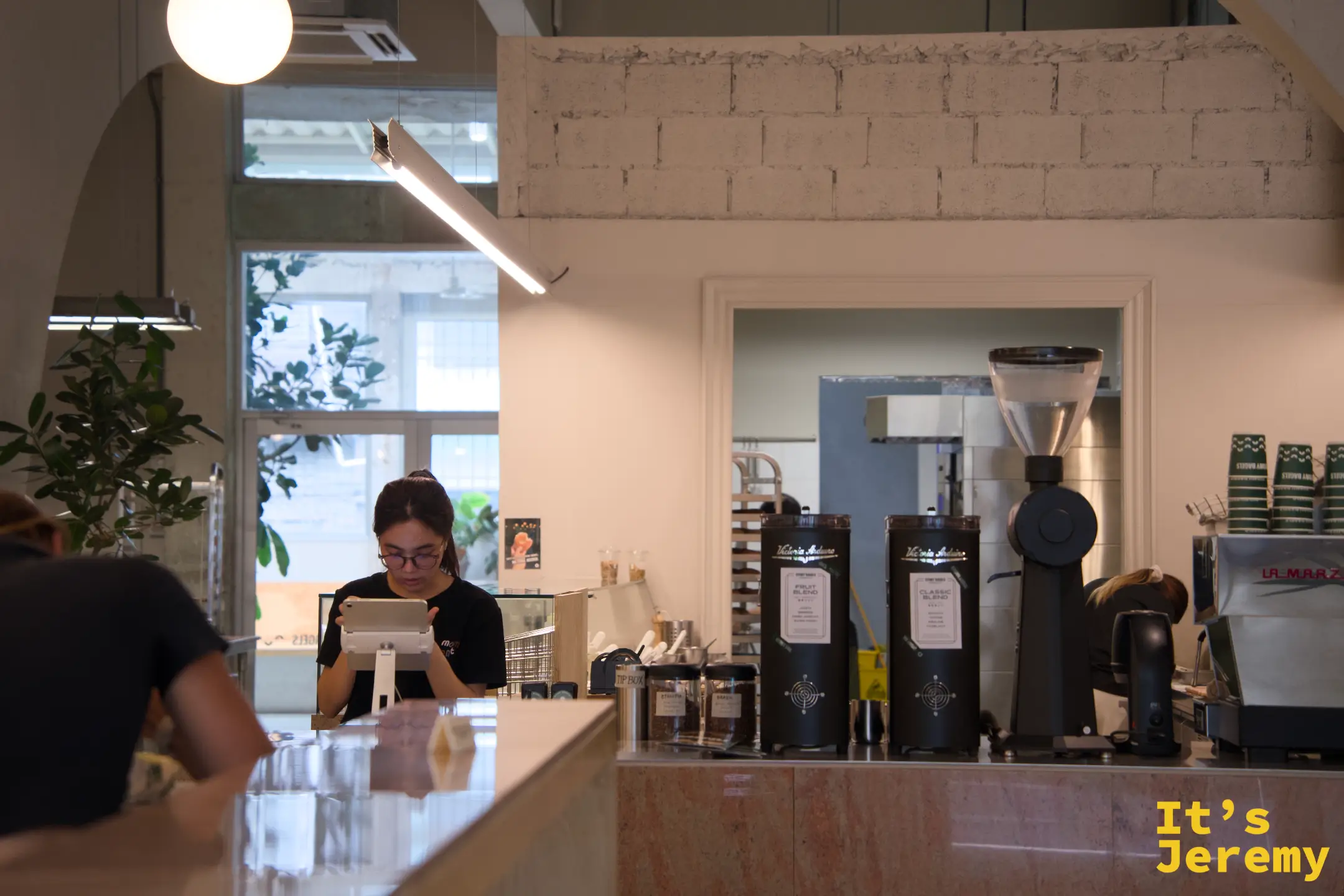 點餐台近景:La Marzocco 咖啡機、Fruit Blend 與 Classic Blend 磨豆機並排,吧台大理石台面整潔