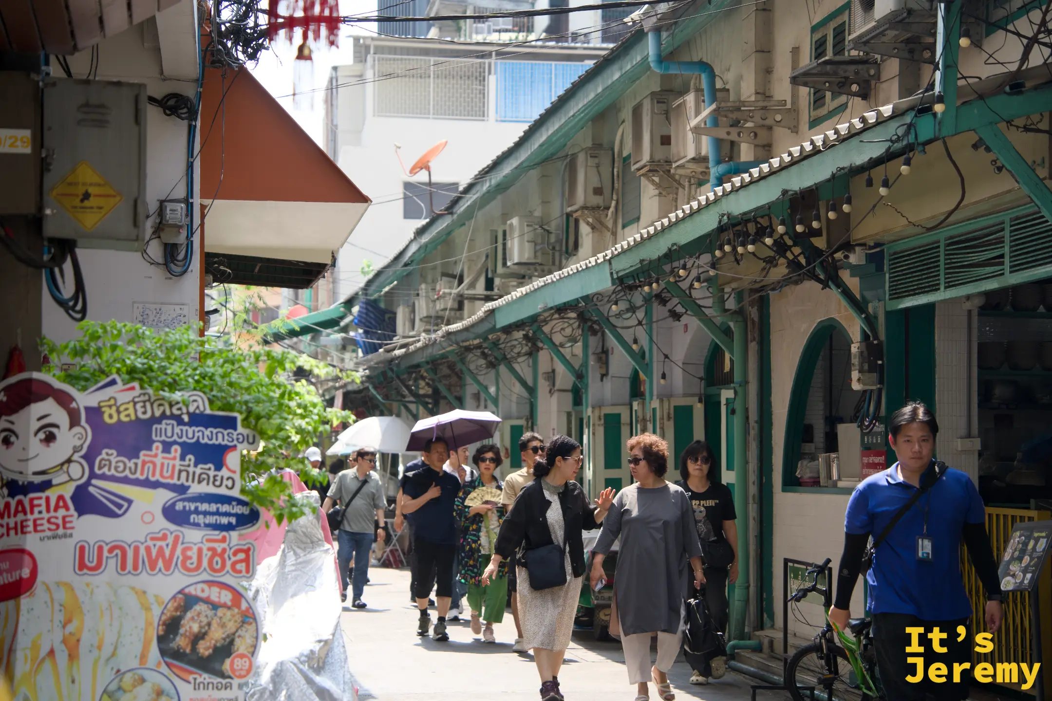 綠色殖民拱廊店屋排開,幾名遊客在廊下走動