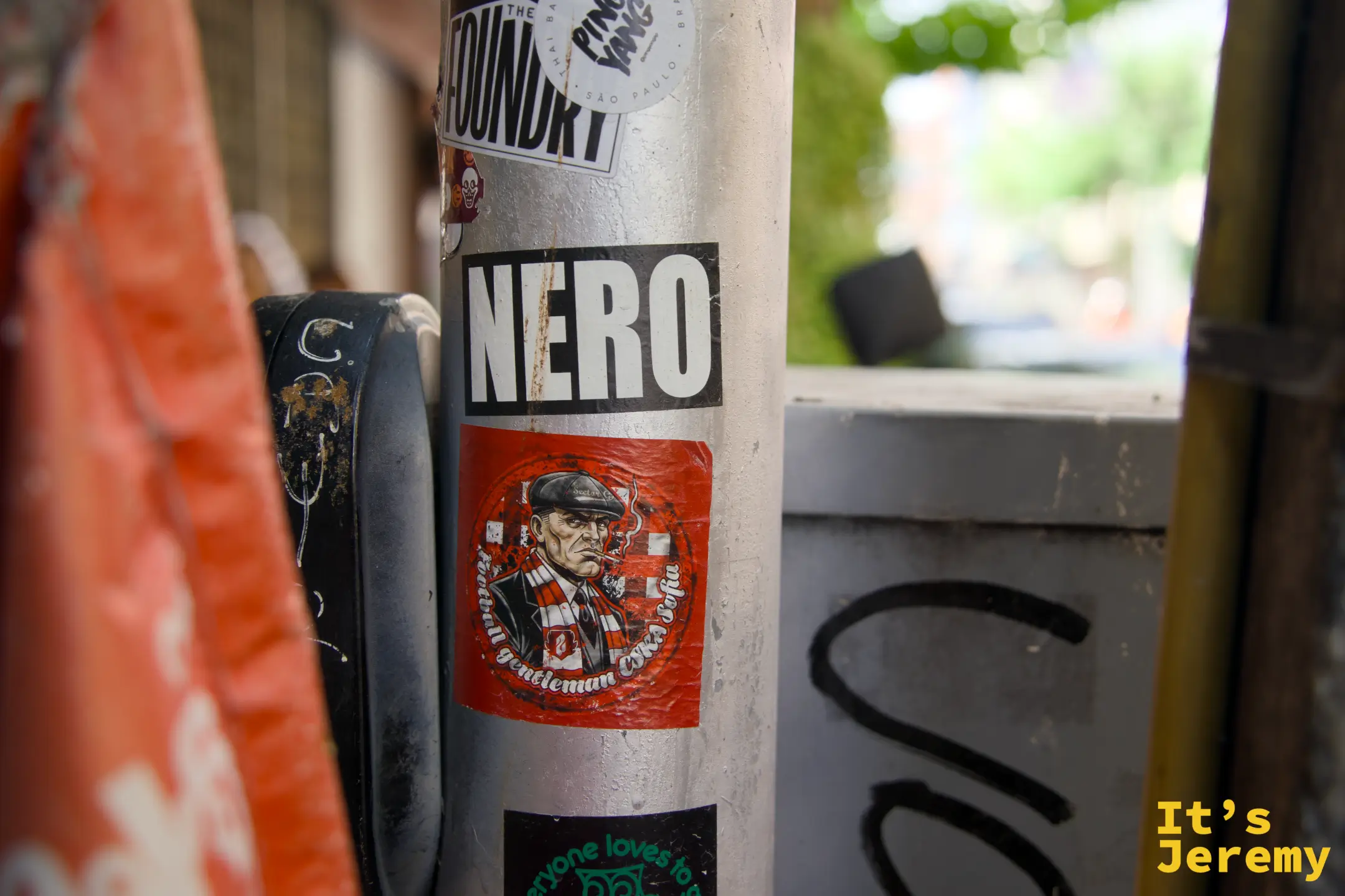 路燈柱上的「NERO」黑白貼紙和紳士插圖,旁邊垂著橘紅色旗幟
