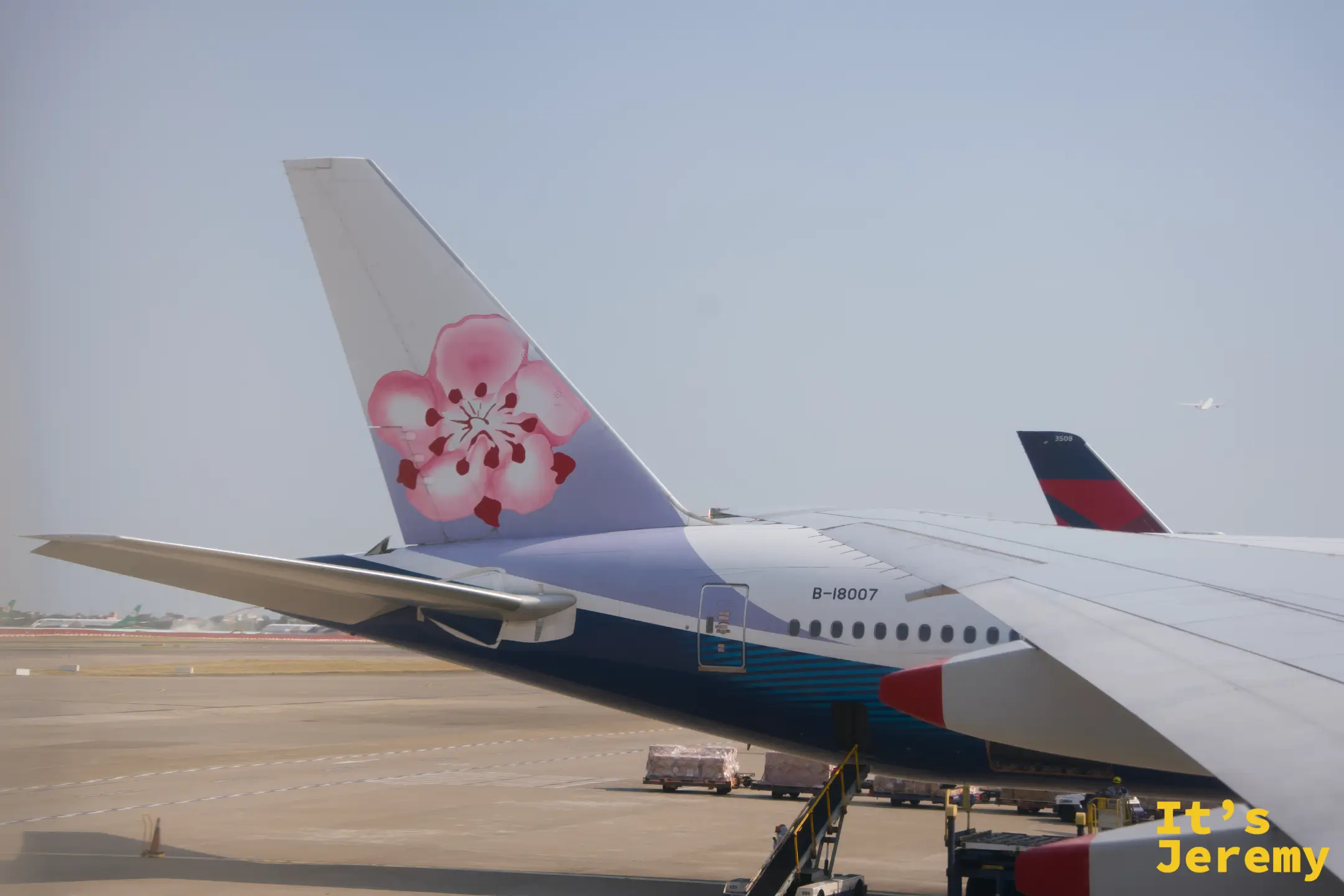 桃園機場停機坪,窗外可見華航梅花尾翼,機身號碼 B-18007,另一側停著達美航班