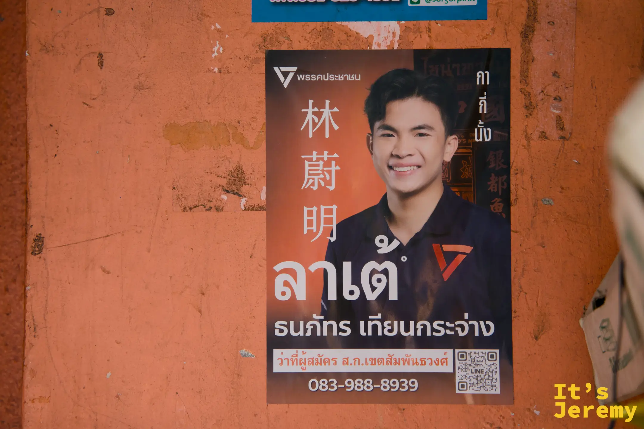 橘色牆面的選區立委候選人競選海報，漢字「林蔚明」與泰文「ลาเต้」雙語並列，嵩越路的多文化日常縮影