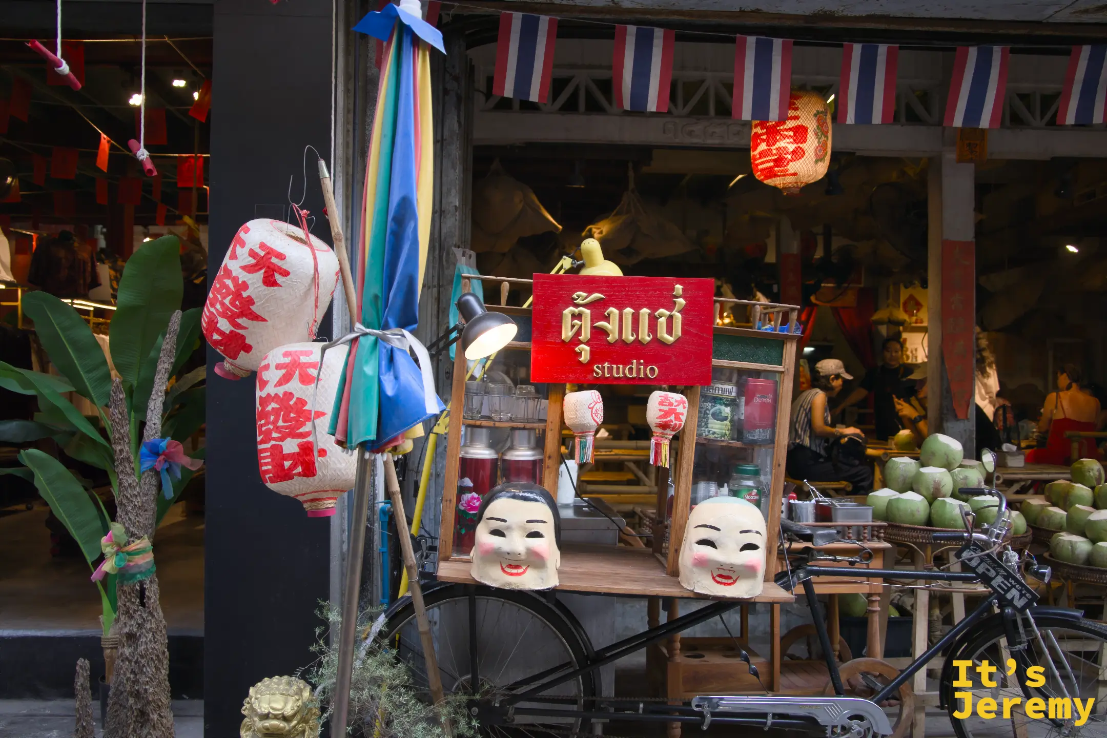 「ตั้งแช่ studio」店前：老腳踏車、中文紅燈籠、舞獅臉具與彩色小旗，民俗感強烈的街頭布置