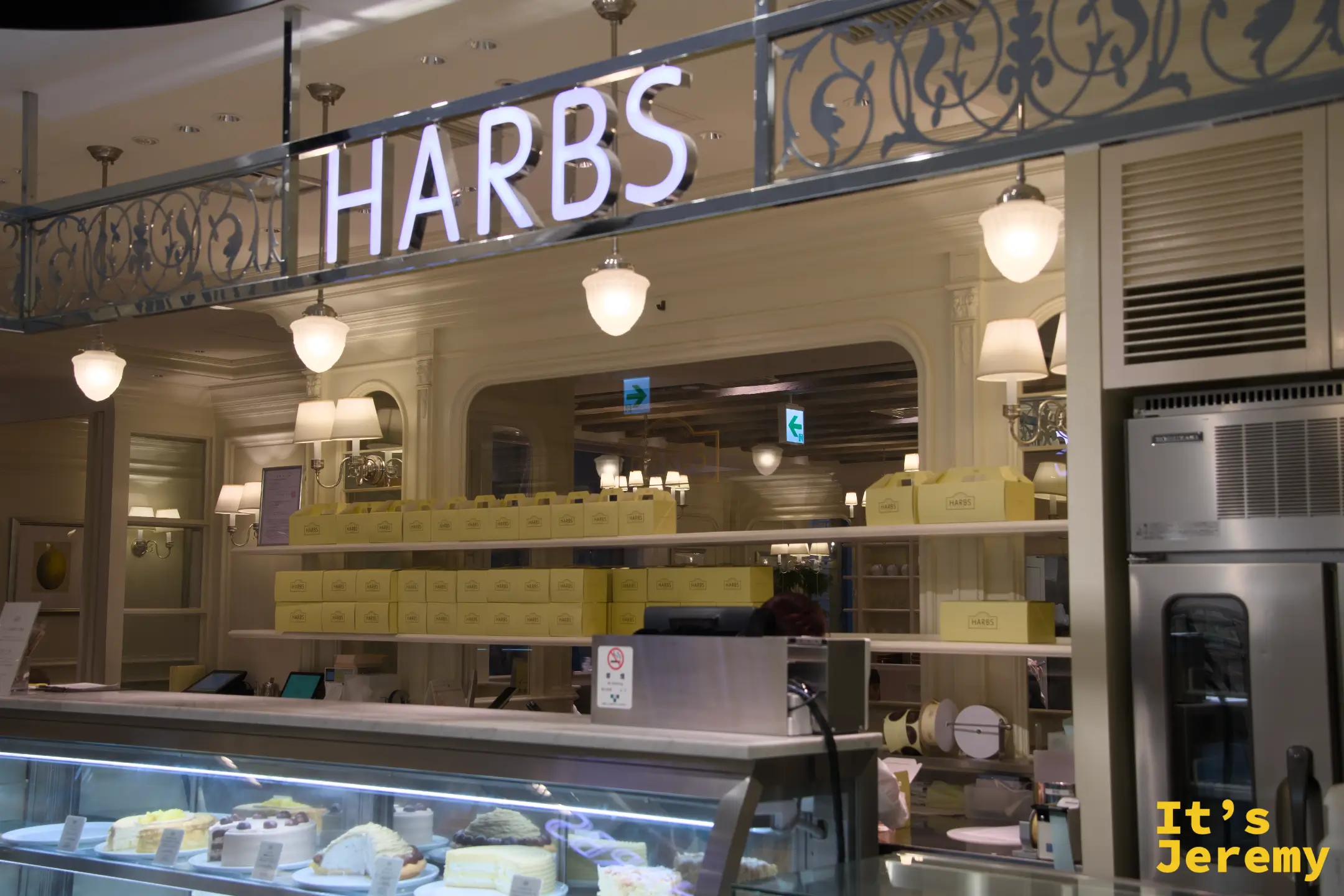 HARBS 門面，HARBS 字樣發光招牌與鐵藝裝飾，門口展示台陳列著各種切片蛋糕