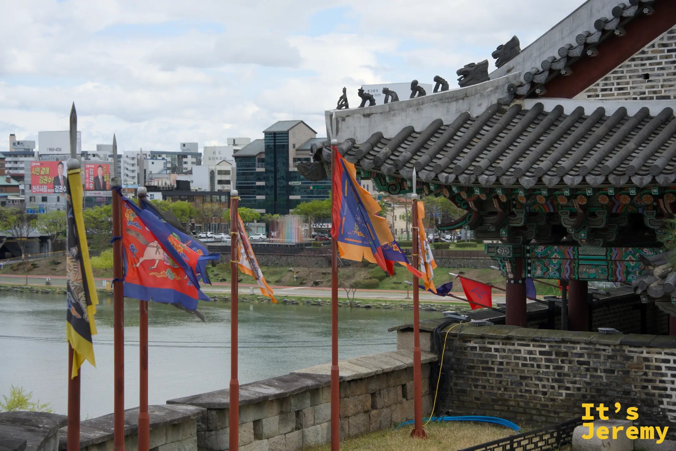 城垛上橙藍軍旗飄揚，矗石樓在側，南江在遠方靜靜流淌