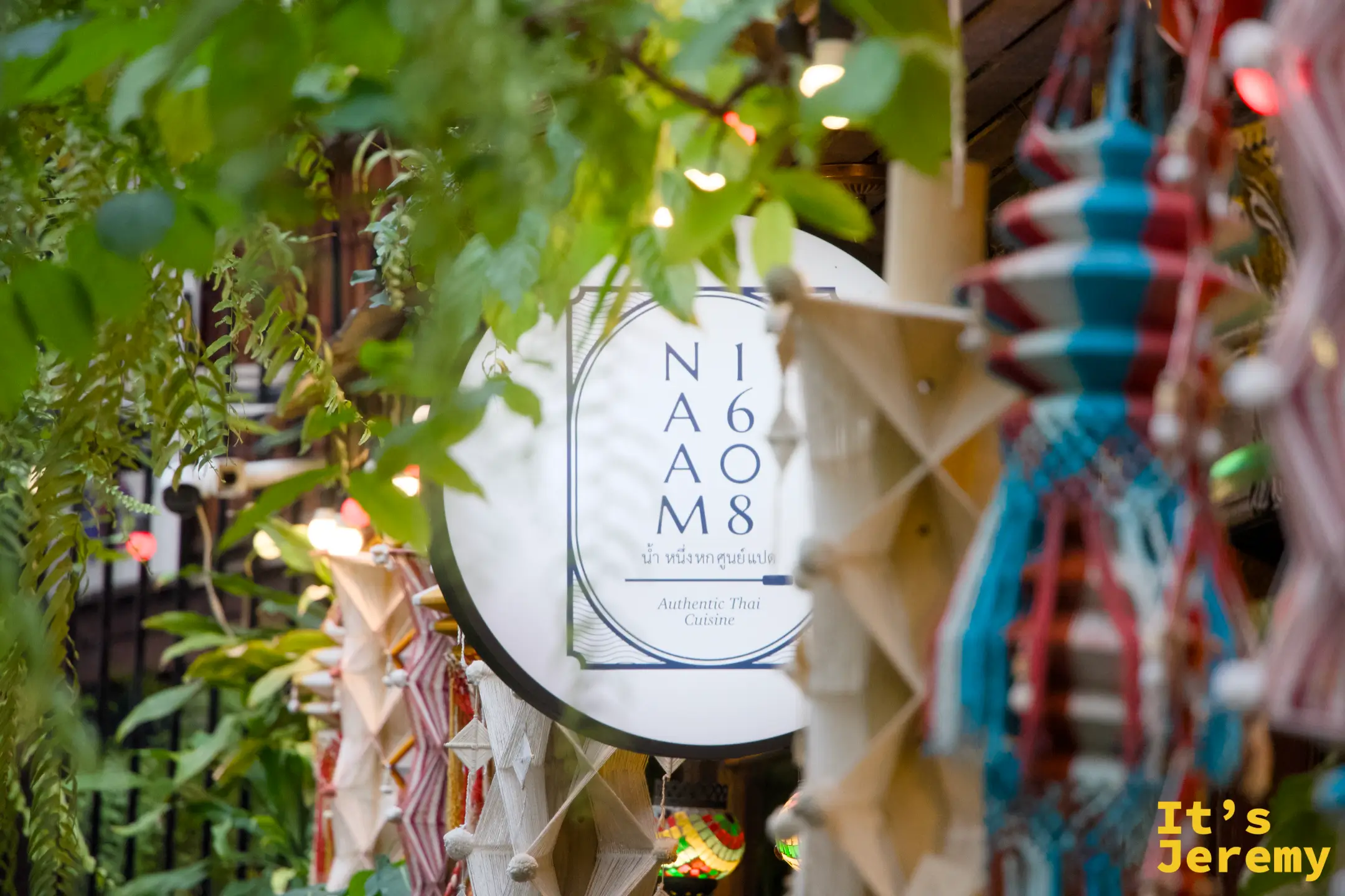 NAAM 1608 招牌被蕨類與手工編織飾品環繞,暖光打在招牌圓盤上