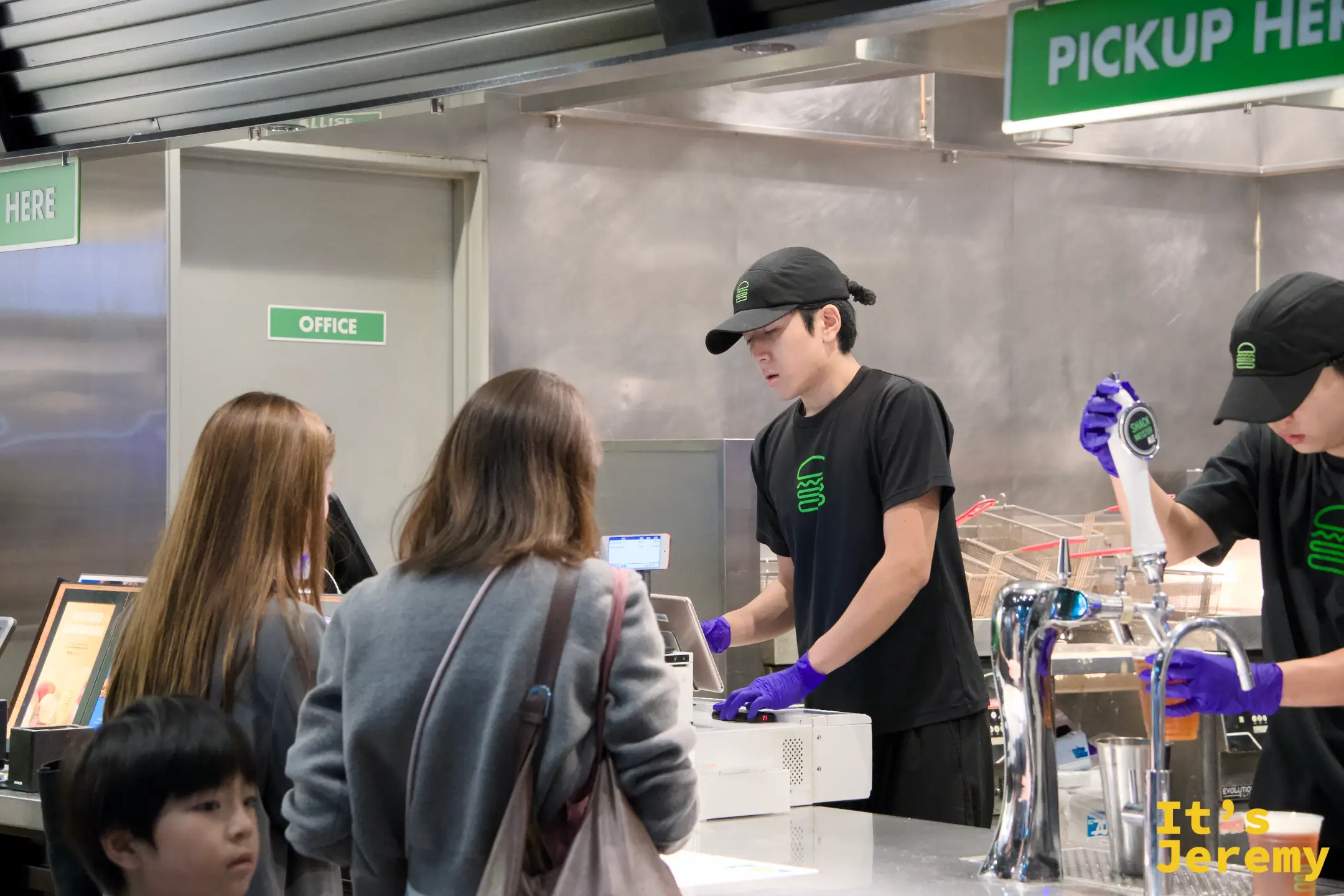 點餐台,顧客在人工櫃台前排隊,店員正在確認訂單,後方生啤機區域同時在出餐
