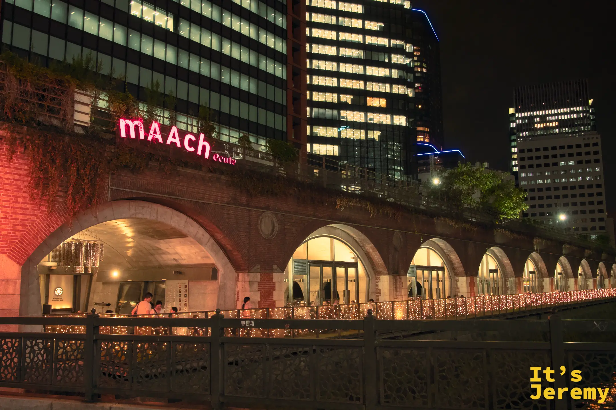mAAch ecute 神田萬世橋 入夜後的紅磚拱廊，粉色霓虹招牌亮起，舊鐵道高架下透出暖光