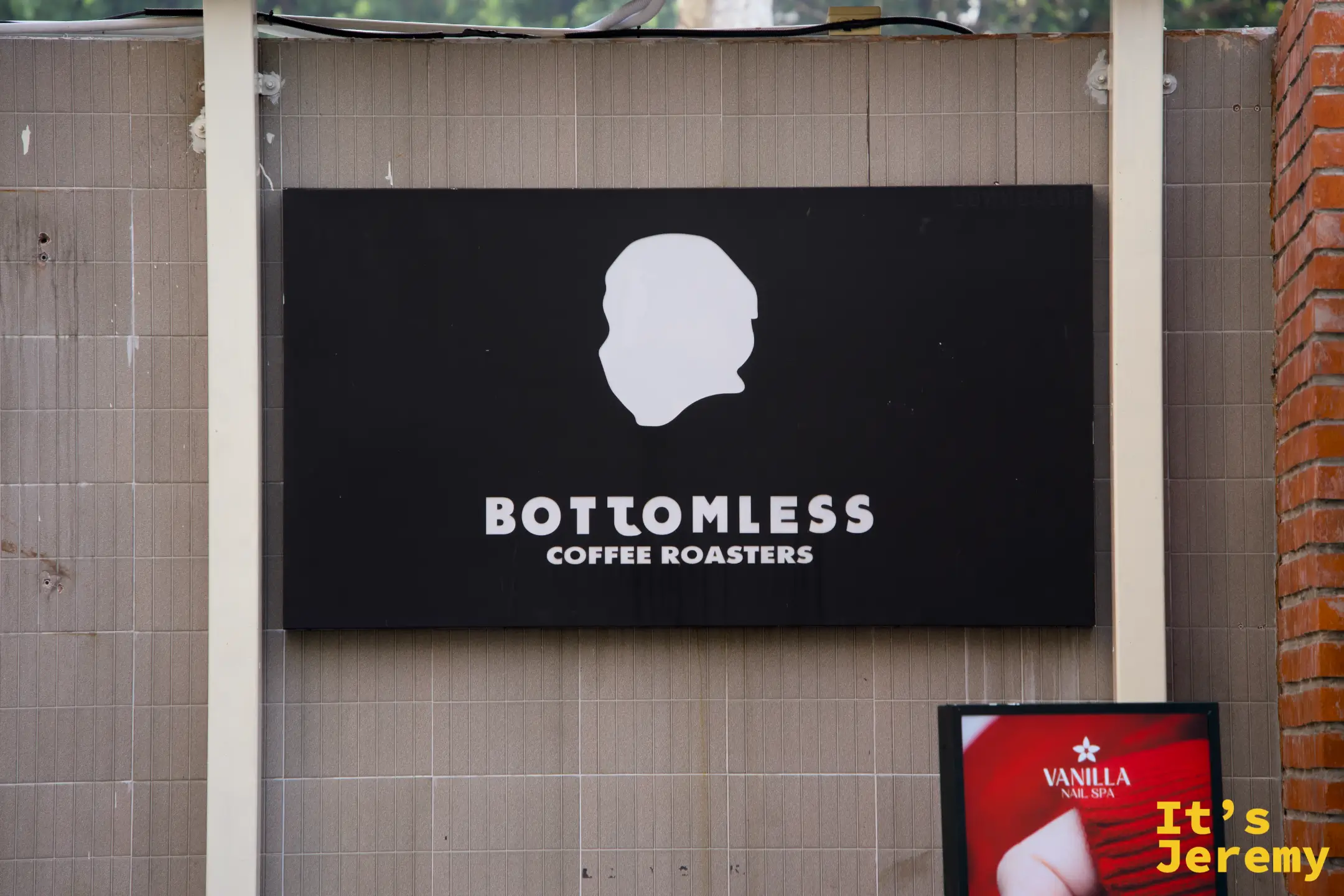 BOTTOMLESS Coffee Roasters 黑底白字 logo 招牌，人頭側面剪影設計