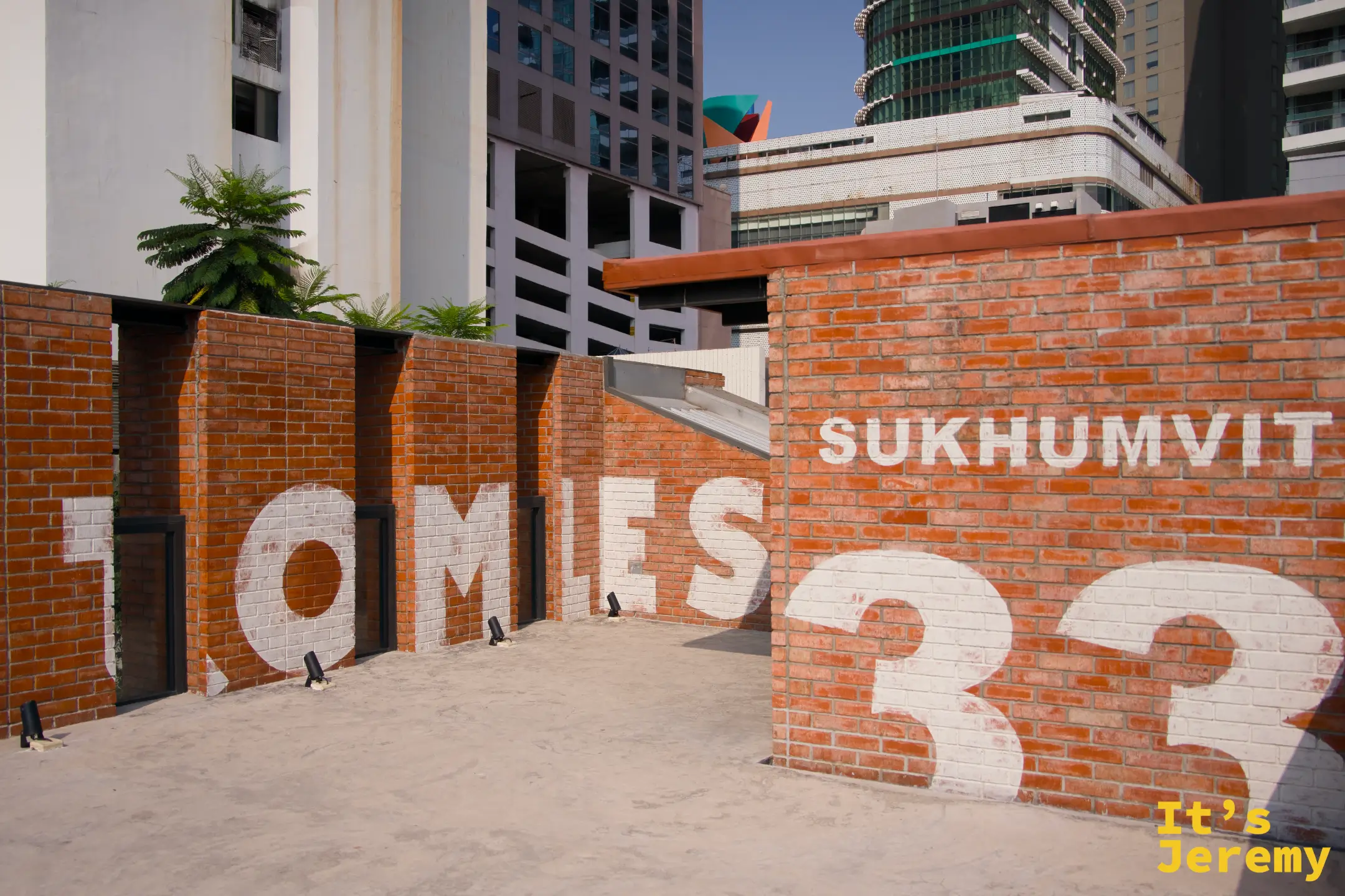 天台「BOTTOMLESS SUKHUMVIT 33」完整字牆，背景曼谷高樓大廈