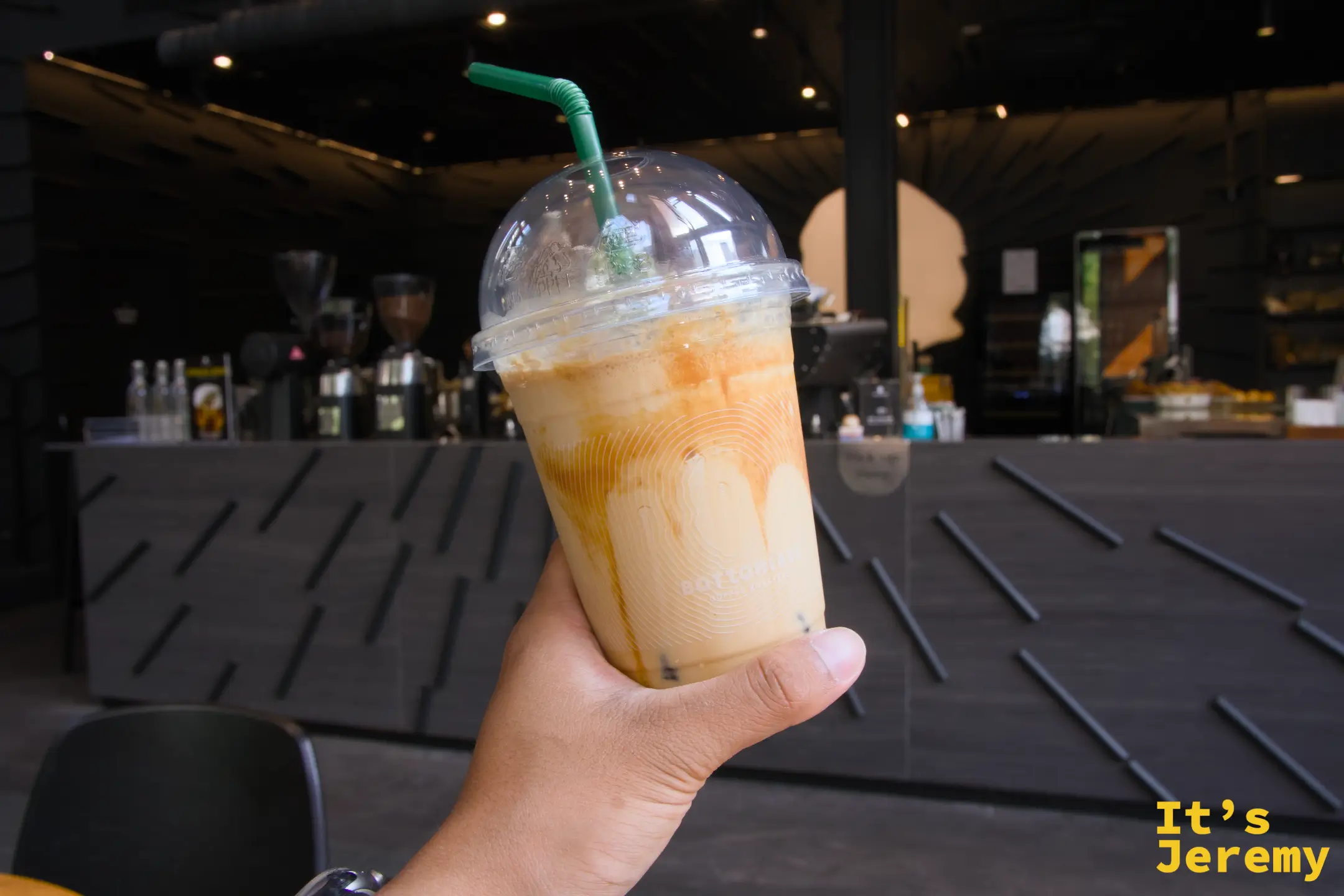 手持 BOTTOMLESS Iced Salted Caramel Macchiato，背景為一樓吧台