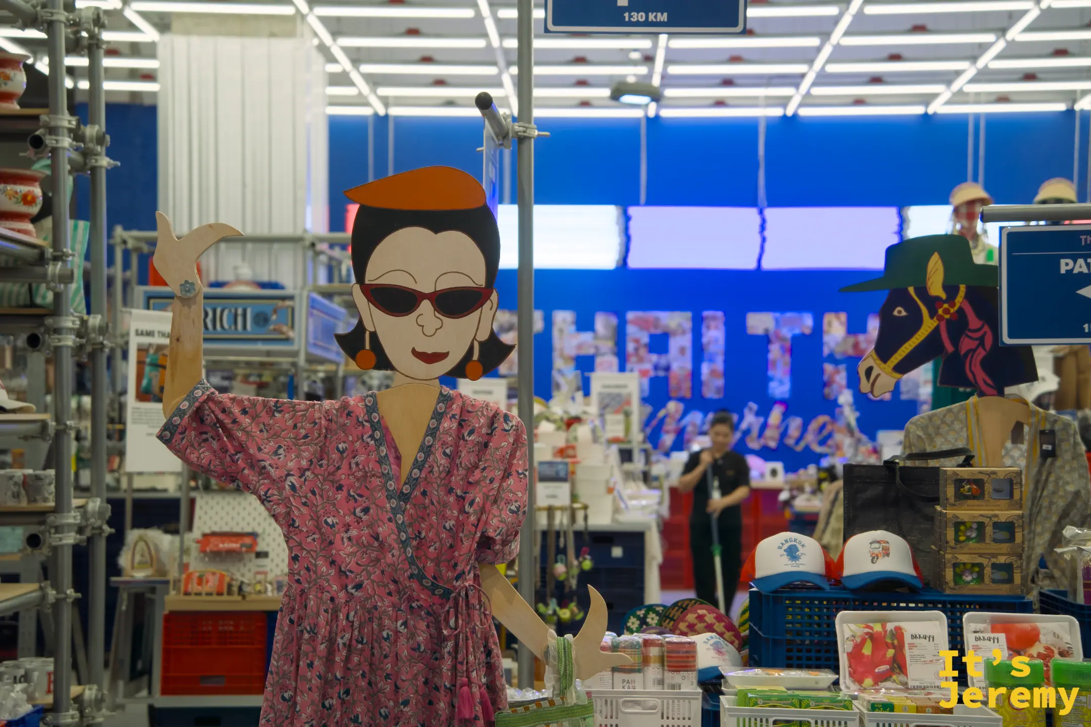 Thai Thai Market 內部,復古插畫紙板剪裁的泰國女性人偶,背景是藍色展示牆與各式紀念品