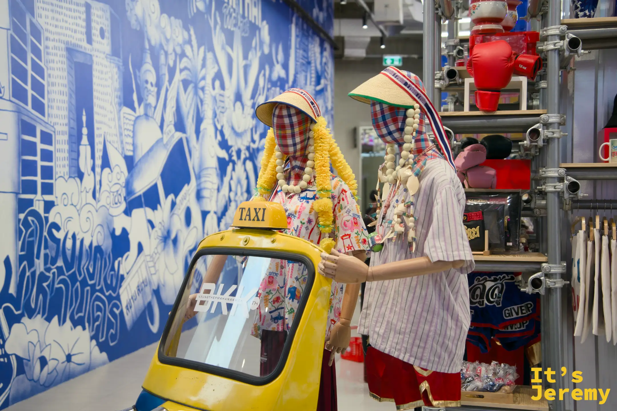 Thai Thai Market,嘟嘟車與身著泰式服裝假人並陳,背景是藍白色泰式城市插畫壁畫