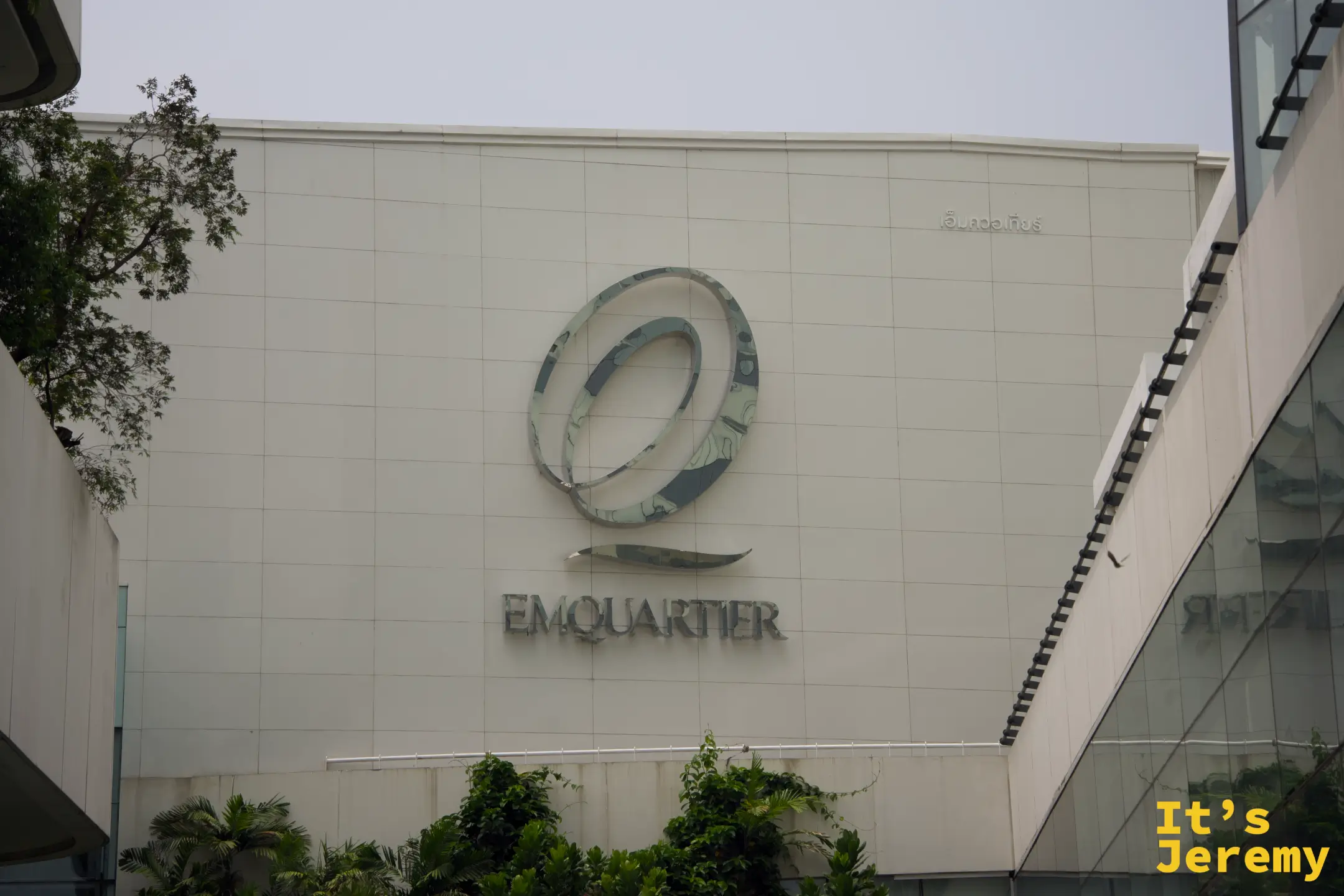 EmQuartier 外觀正面,標誌性的「@」形 logo 在白色外牆上,藍天背景