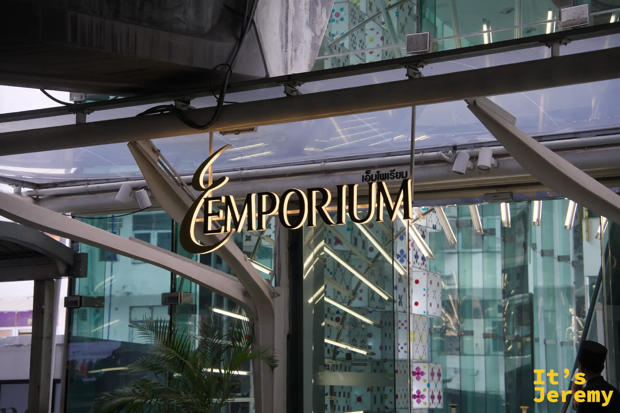 Emporium 入口玻璃頂棚下的金色「EMPORIUM」燙金招牌,有保安站在旁邊