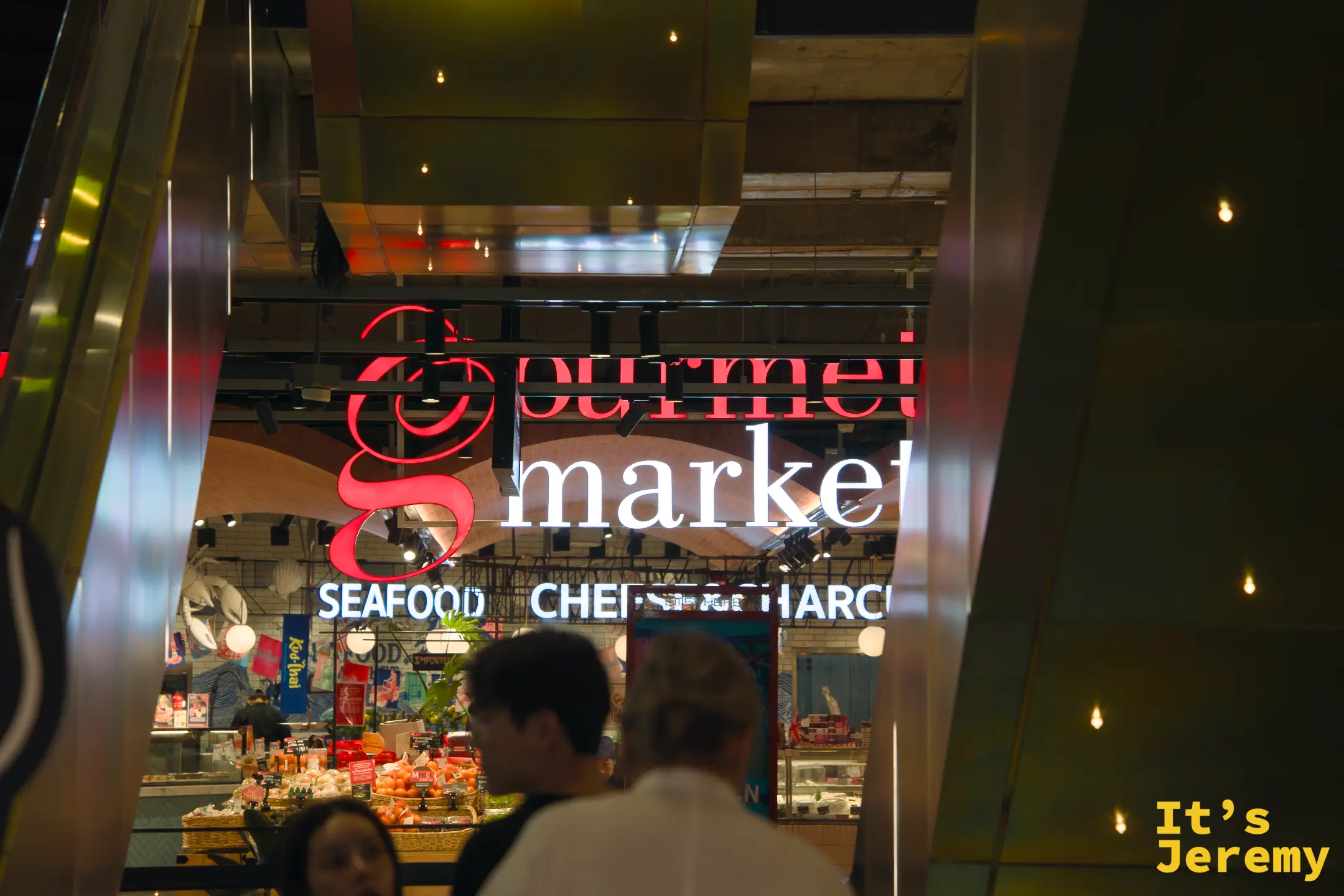 夜晚從外部框景看 Gourmet Market,拱形構圖,店內人來人往