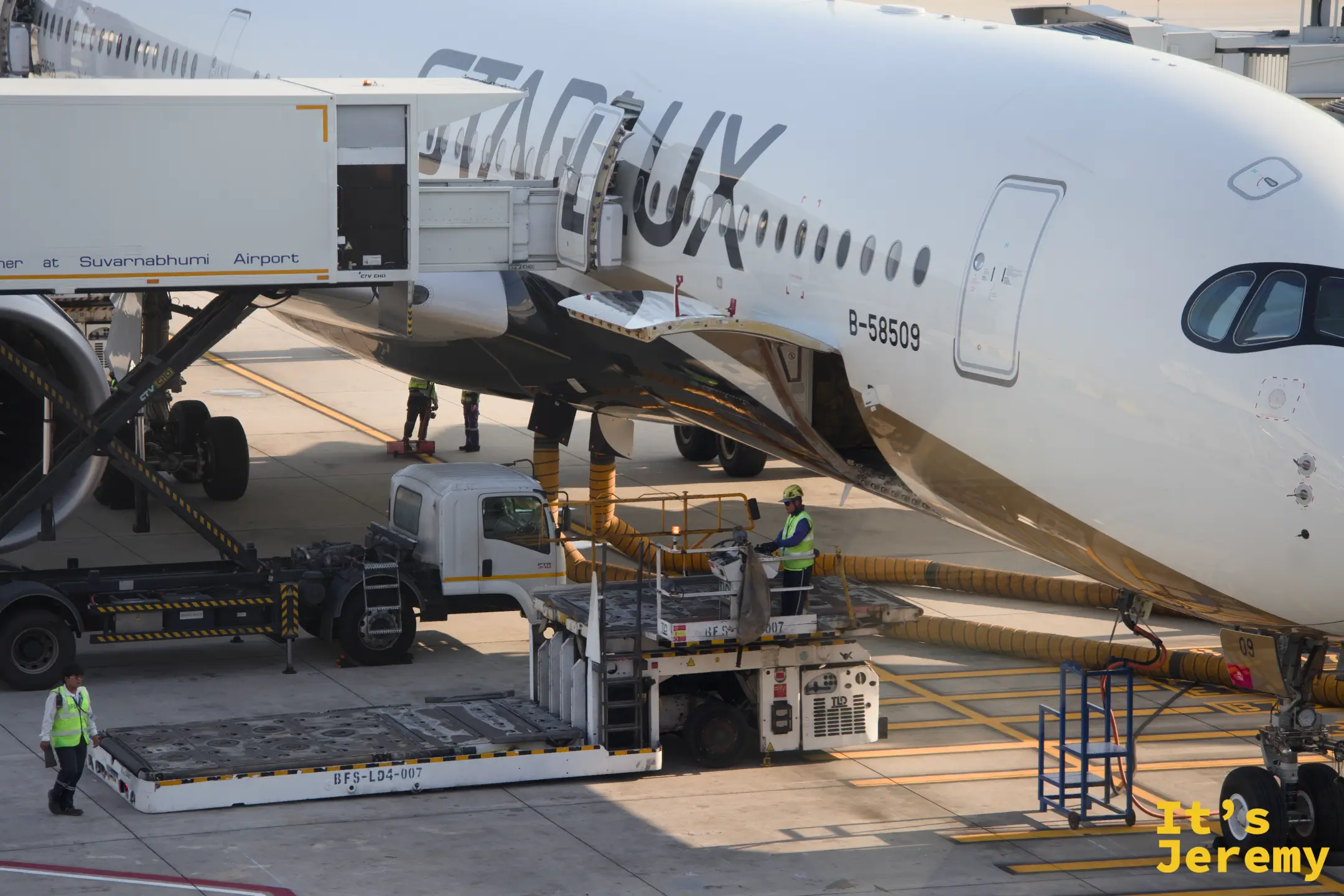 停機坪上地勤人員對星宇航空 STARLUX 飛機機腹進行加油作業,黃色油管連接著機身