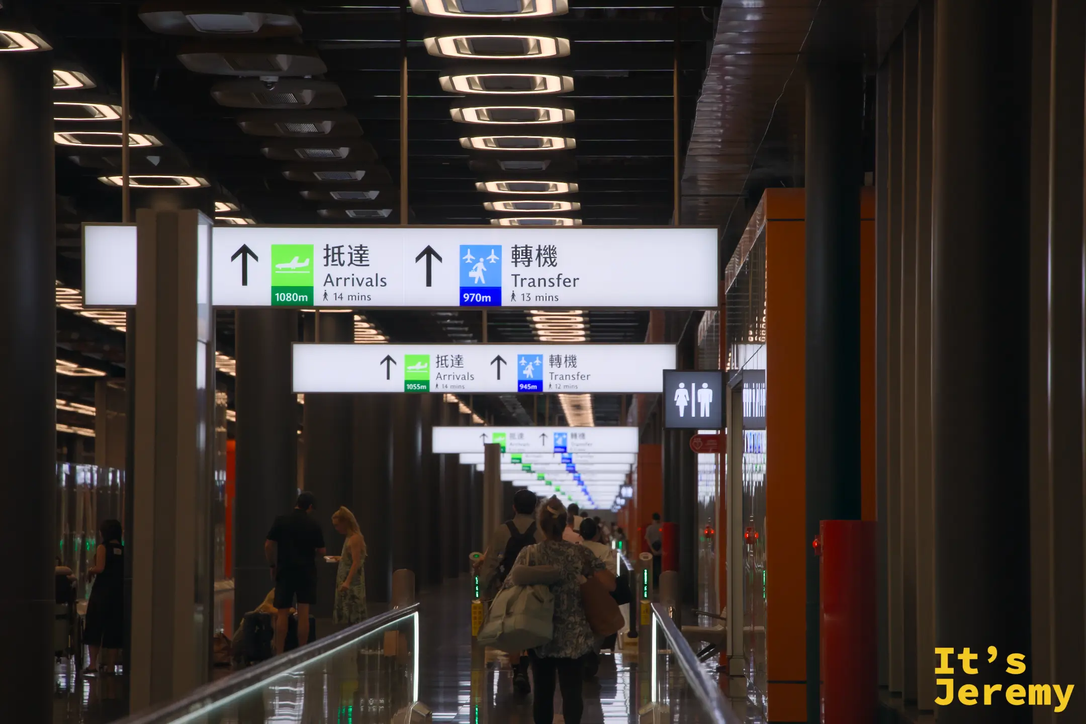 桃園機場第三航廈入境走廊,抵達 Arrivals 和轉機 Transfer 指示看板,旅客正在行走