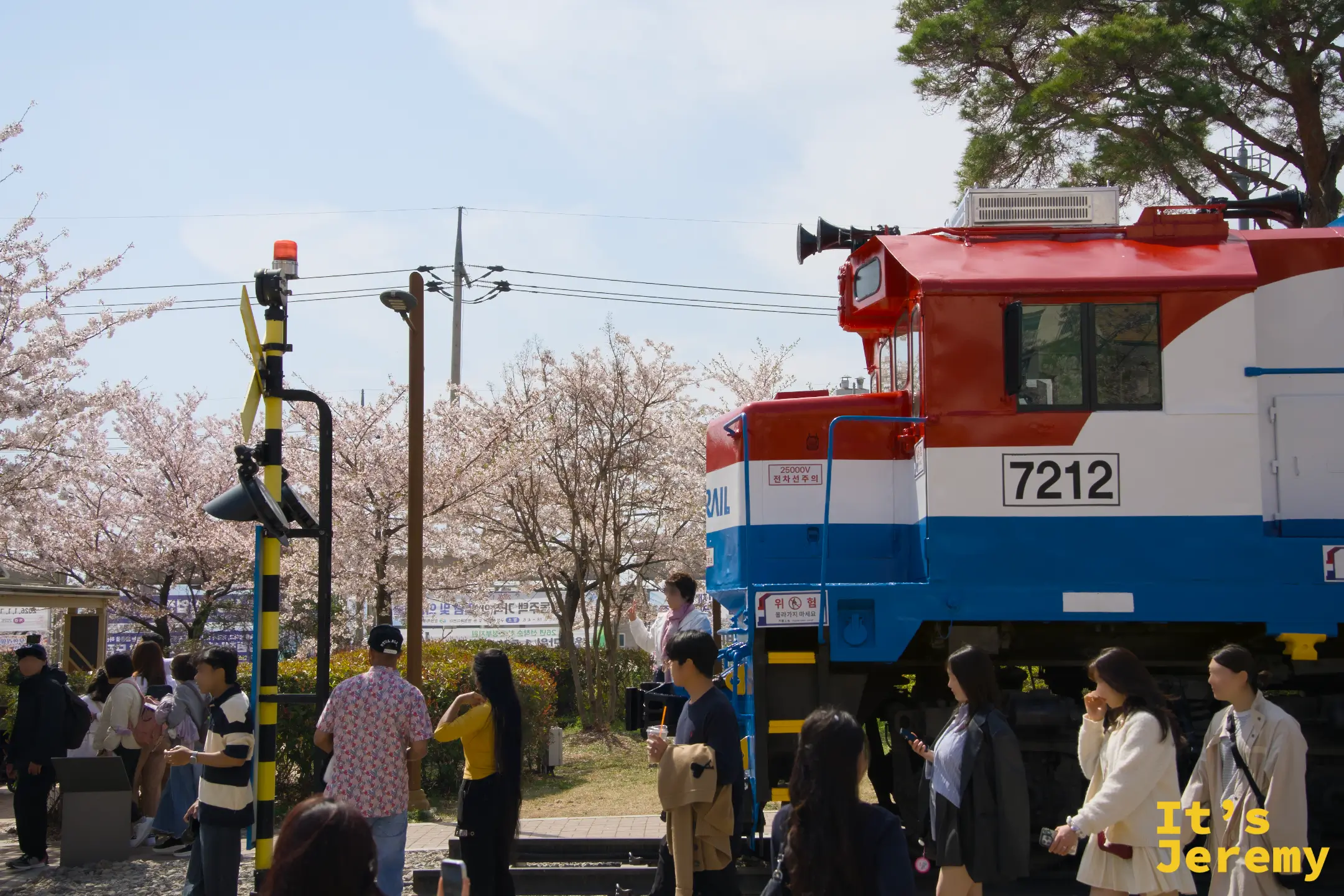 KORAIL 7212 號機車頭的側面近景，和拍照的旅人形成有趣的對照