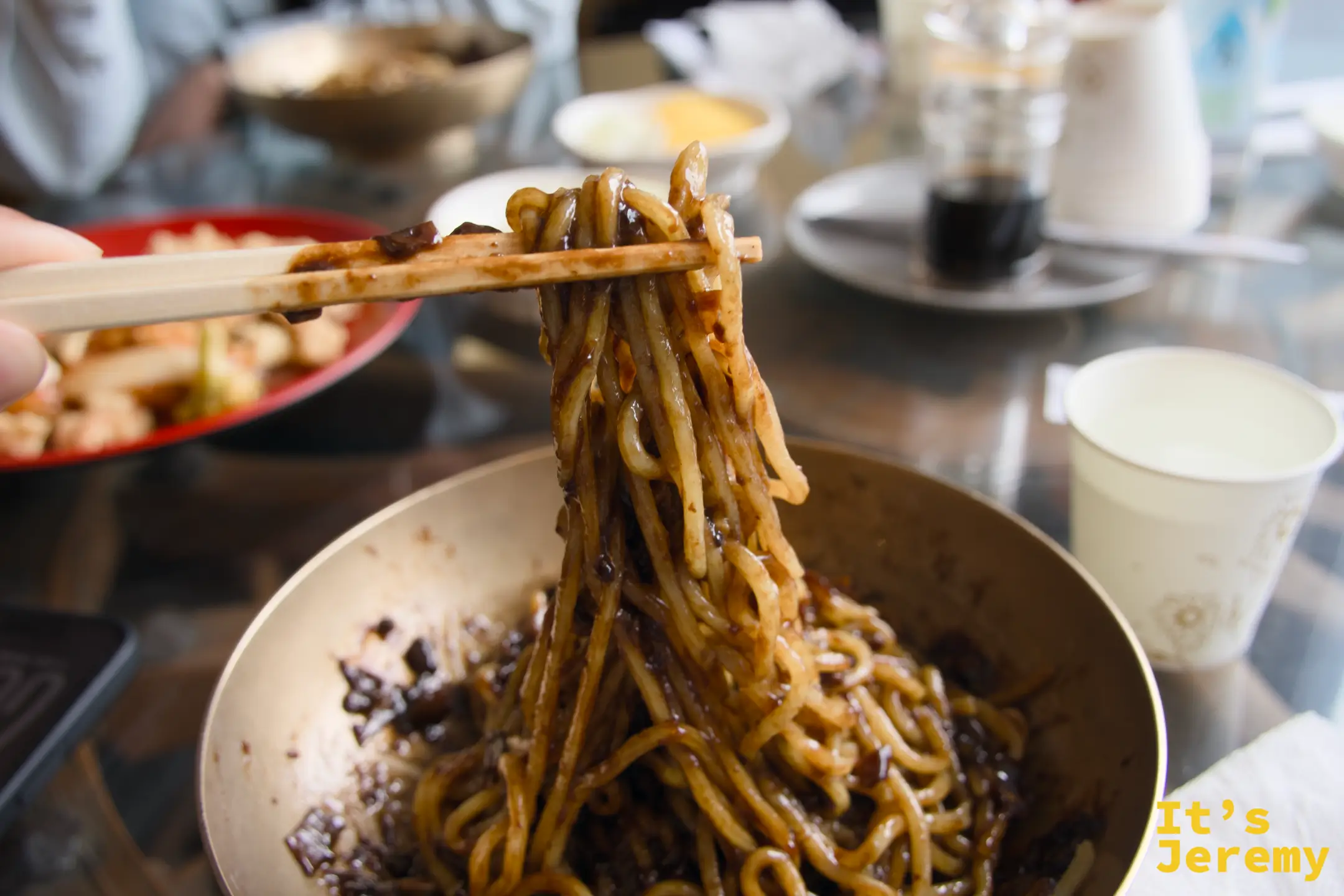 用筷子挑起的炸醬麵，黑亮醬汁裹滿每一條麵，視覺上就已先飽