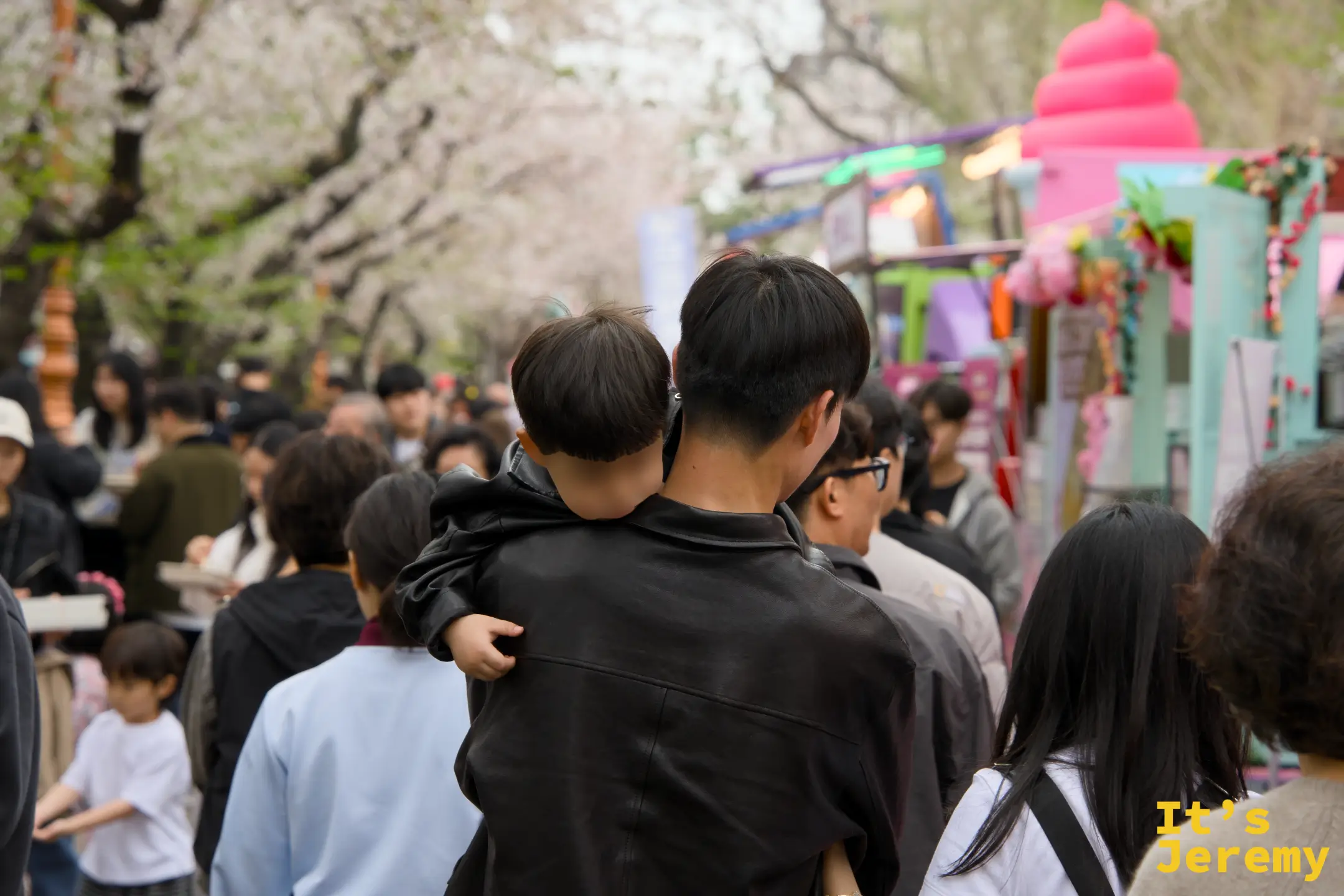 爸爸背著已經打瞌睡的小孩繼續在花道人群中穿行,右側是五顏六色的食物攤車——這個畫面大概是軍港祭最溫馨的紀實角度