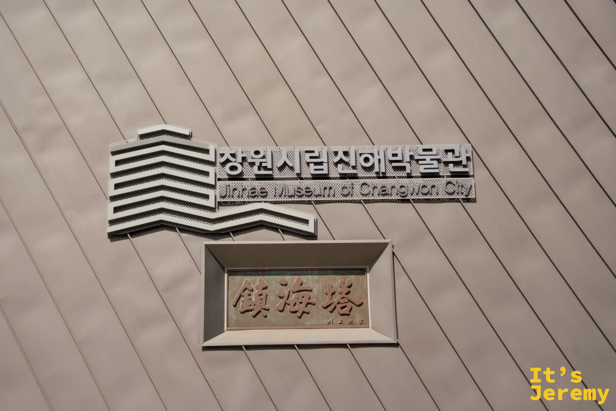 昌原市立鎮海博物館外牆,上方為博物館英韓文名稱,下方是刻著「鎮海塔」的銅色牌匾