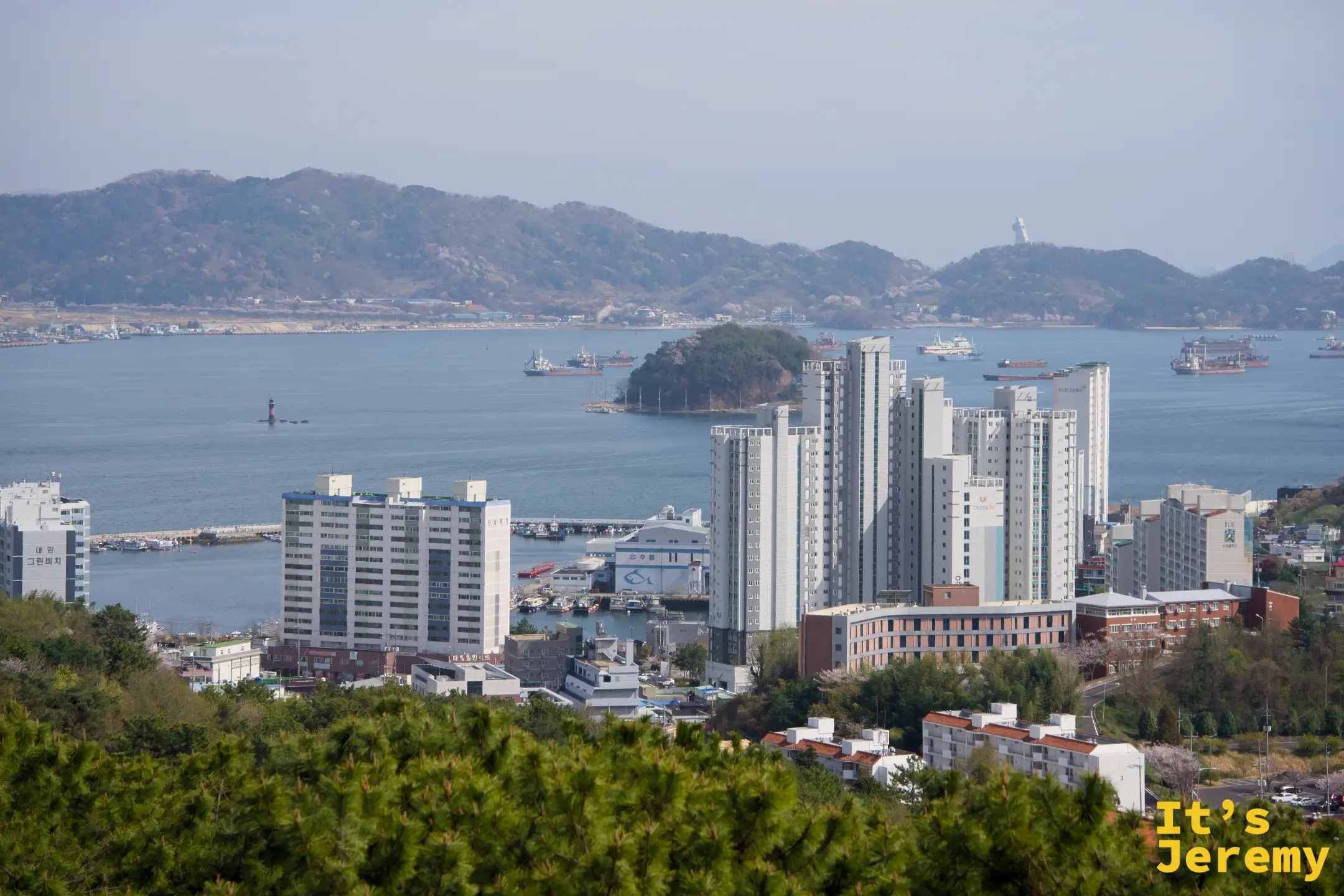 從鎮海塔眺望鎮海港灣,高樓沿海岸林立,遠方群山層疊,海面上可見船隻穿梭出沒
