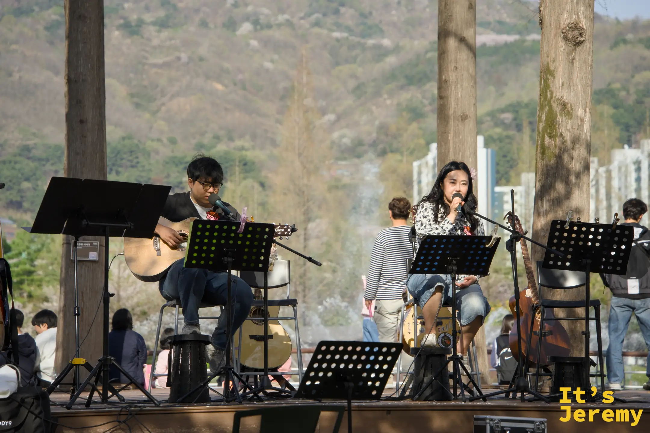 戶外表演台上樂團現場演出，山脈與城市天際線作為自然背景