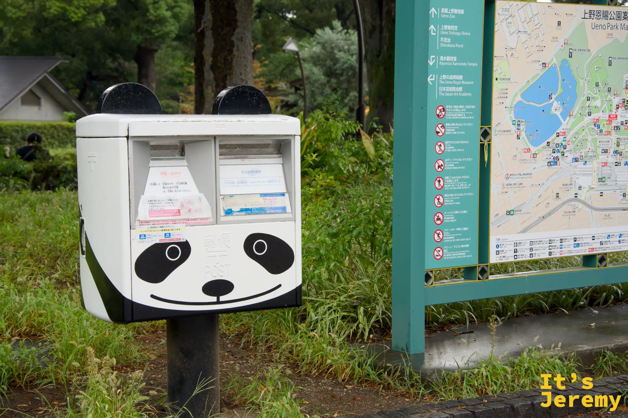 上野公園入口旁的熊貓造型收集箱,白色機體配上黑色眼鼻,旁邊是上野公園的區域地圖指示牌