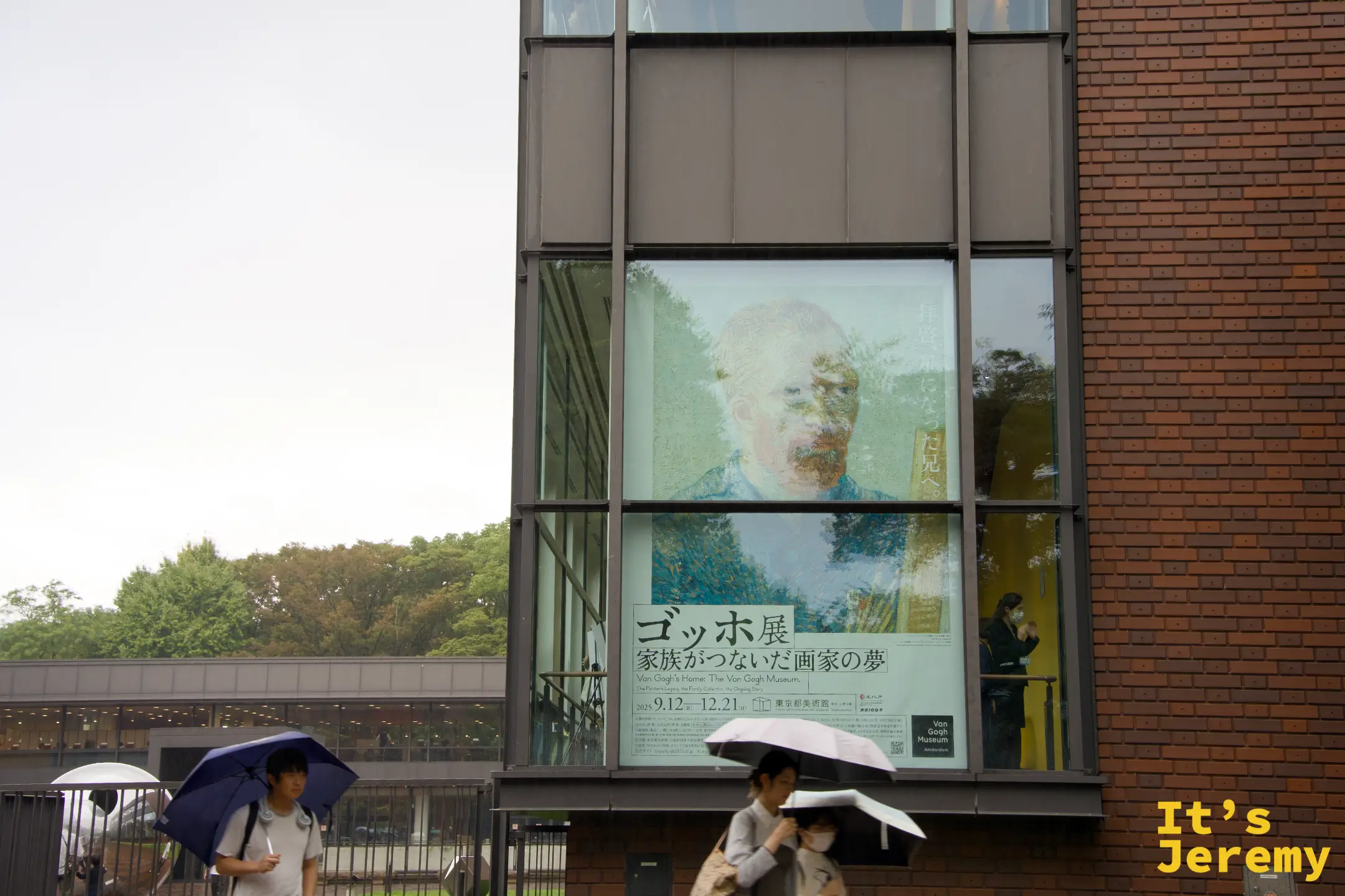 東京都美術館建築的大型玻璃外牆,映著梵谷展「ゴッホ展 家族がつないだ画家の夢」的宣傳海報,梵谷的臉透過玻璃反光以一種奇特的方式浮現在磚牆和樹影之間