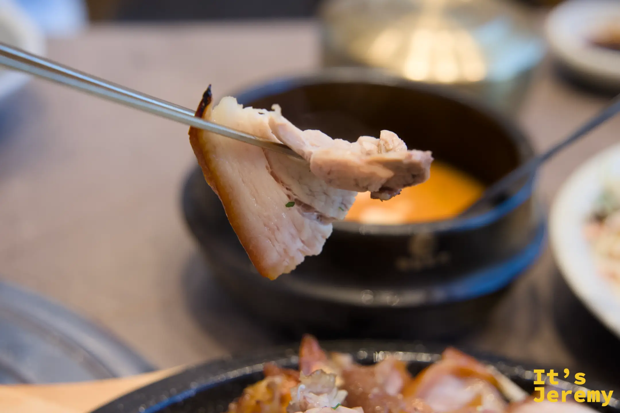 用筷子夾起一片族發，皮與肉的層次清晰可見