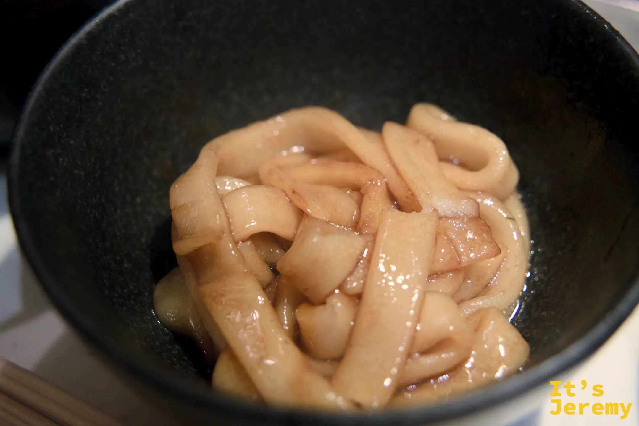 締め麵料理，捲曲麵條盛在深色陶碗中