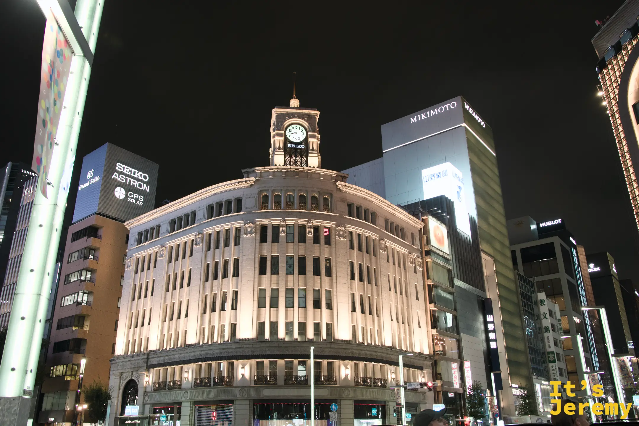 銀座夜景,和光百貨的古典鐘塔建築在夜燈下呈現暖金色,SEIKO ASTRON 和 MIKIMOTO 等招牌在周圍林立,夜空深藍