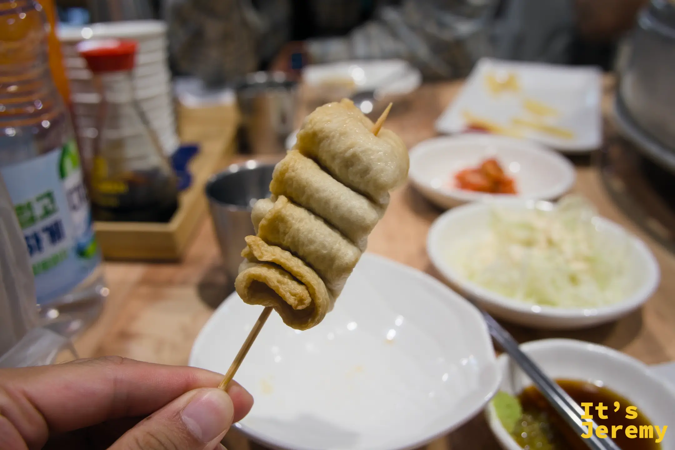 手持一根魚板串，準備沾取桌上的醬料