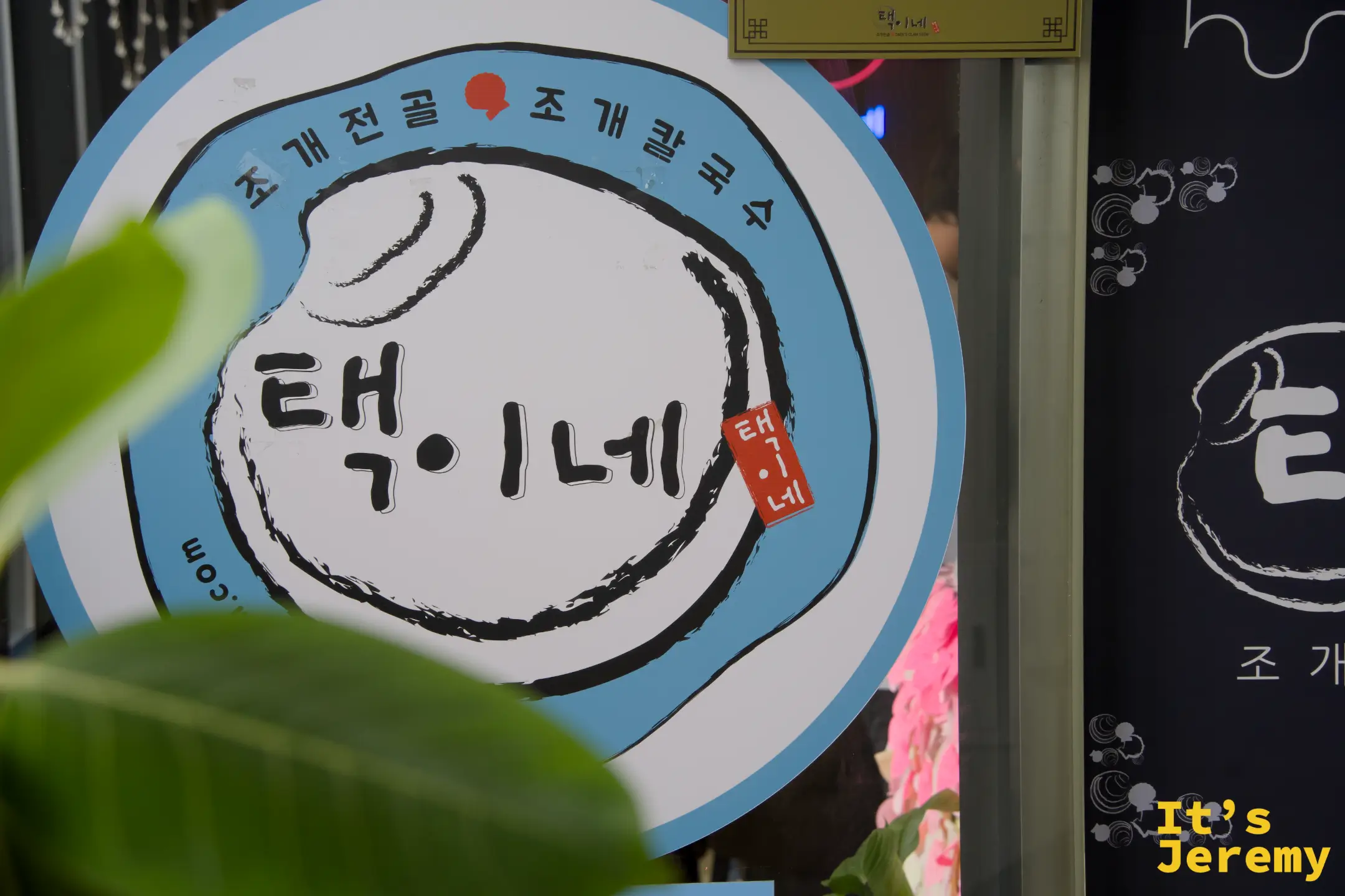 澤家貝殼蒸鍋招牌，藍色圓形 logo 上寫著 택이네，貝殼火鍋與貝殼刀削麵