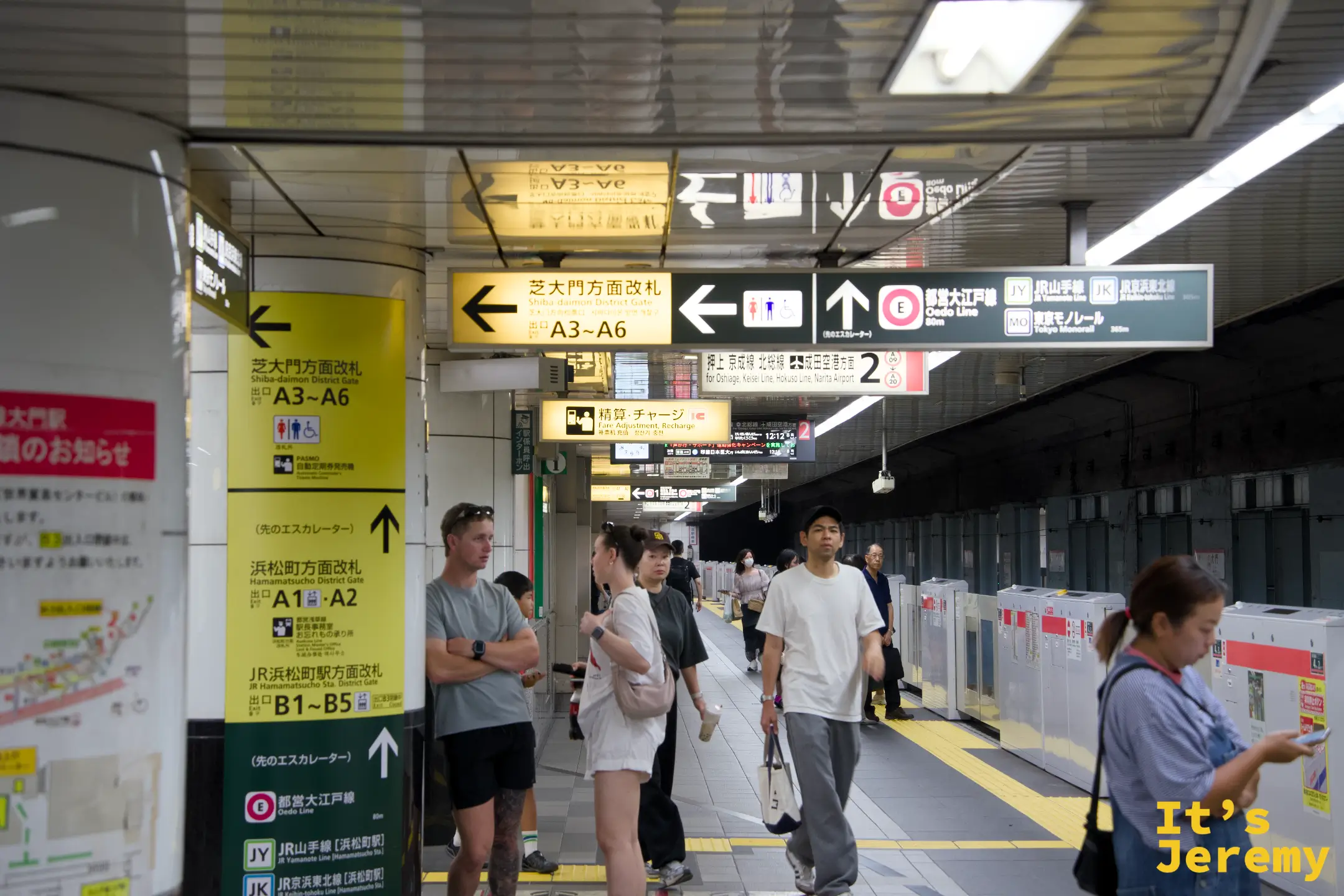 大門駅站內,黃色指示牌標示著「芝大門方面改札」「浜松町方面改札」,通勤客穿梭其間